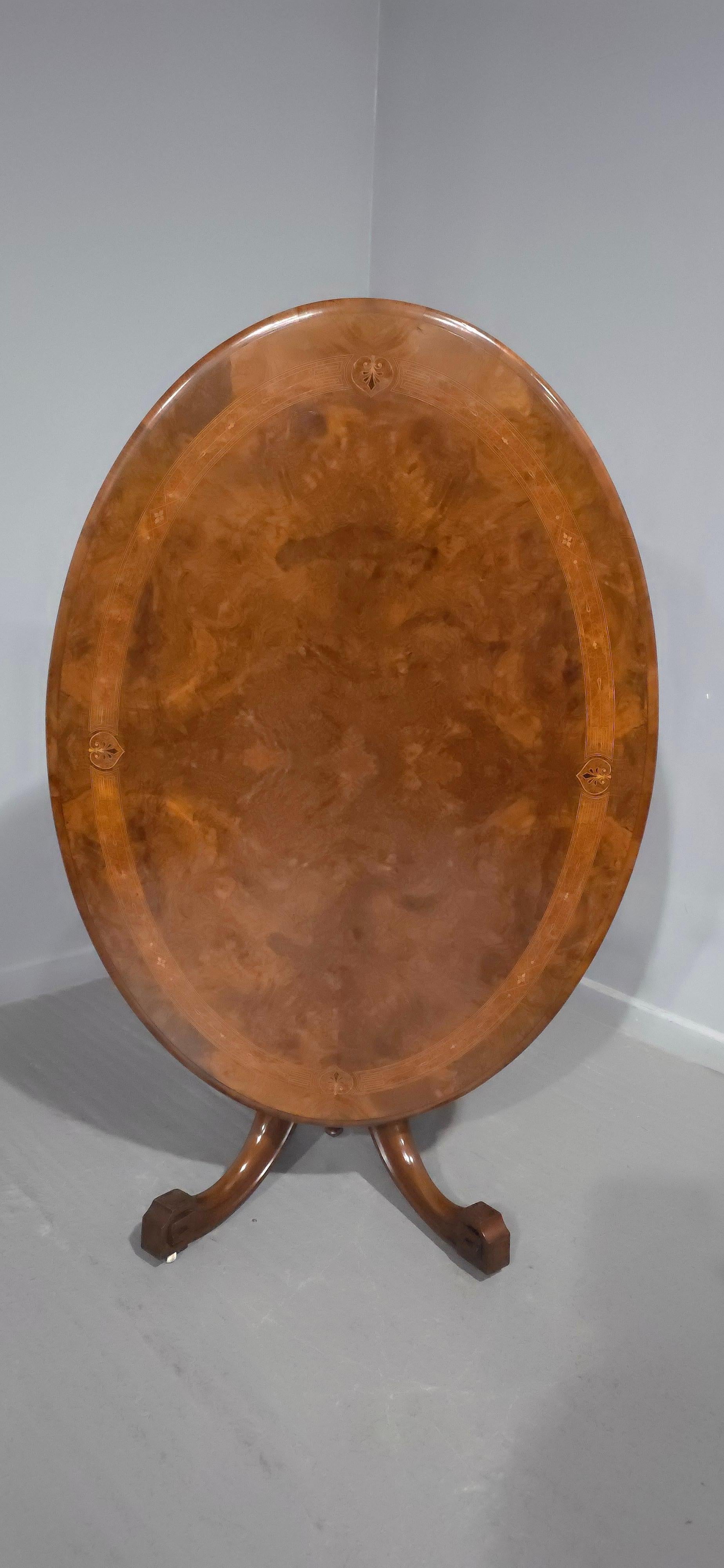 Table à déjeuner ovale victorienne en ronce de noyer et marqueterie, plateau basculant en quart de placage, support à quatre colonnes, pieds sabres avec roulettes d'origine, estampillée BROs, six places assises avec facilité, en très bon état