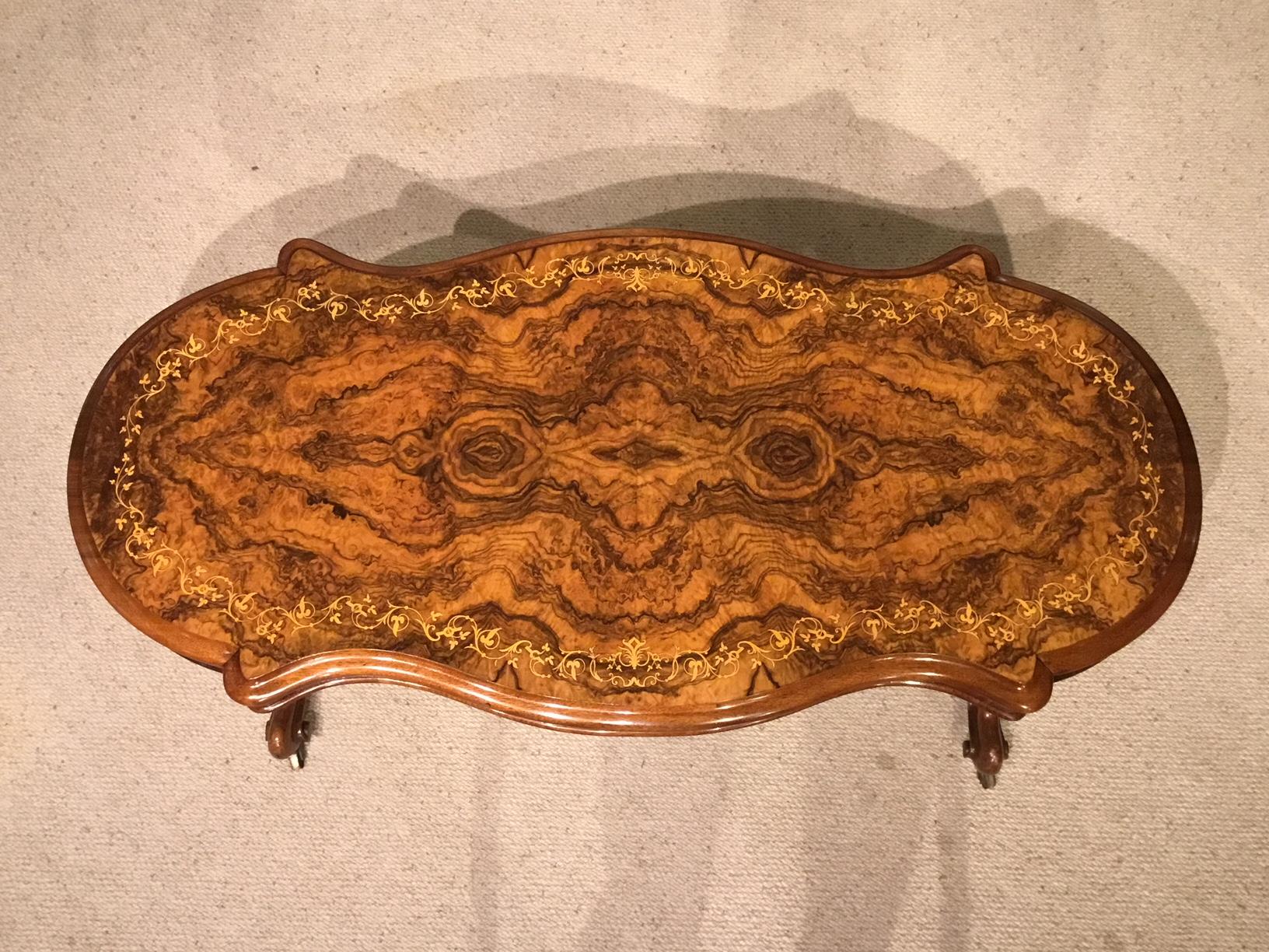 A superb burr walnut Victorian Period serpentine coffee table. The serpentine shaped top veneered in the finest burr walnut with foliate marquetry inlaid detail to the border. Having a burr walnut veneered frieze and supported on turned and carved