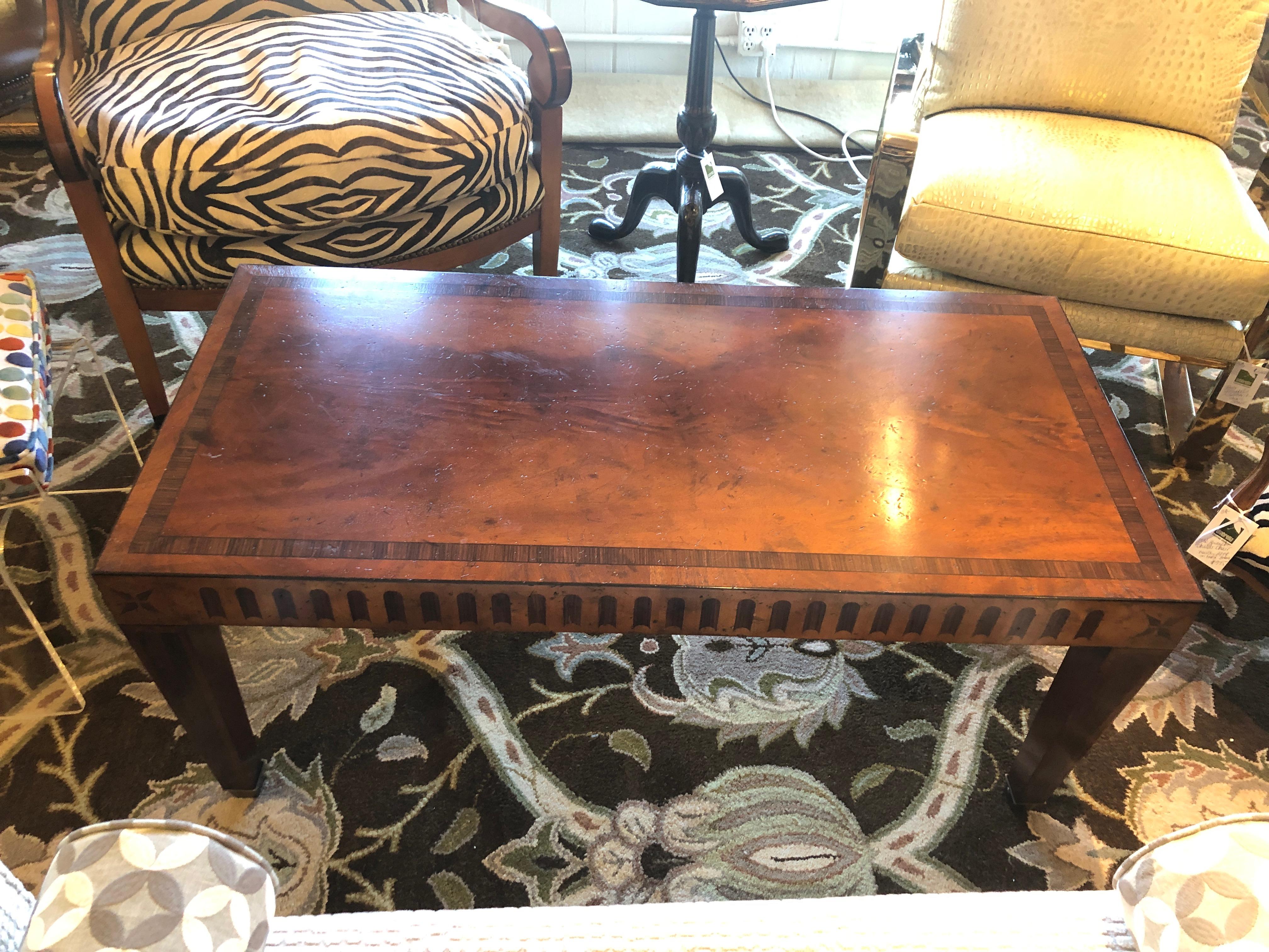 A handsome crotch mahogany rectangular coffee table having beautiful mixed wood inlay with neoclassical shapes including diamonds, star shapes and key holes. The tapered legs terminate in brass capped feet. Sturdy, heavy and beautifully crafted