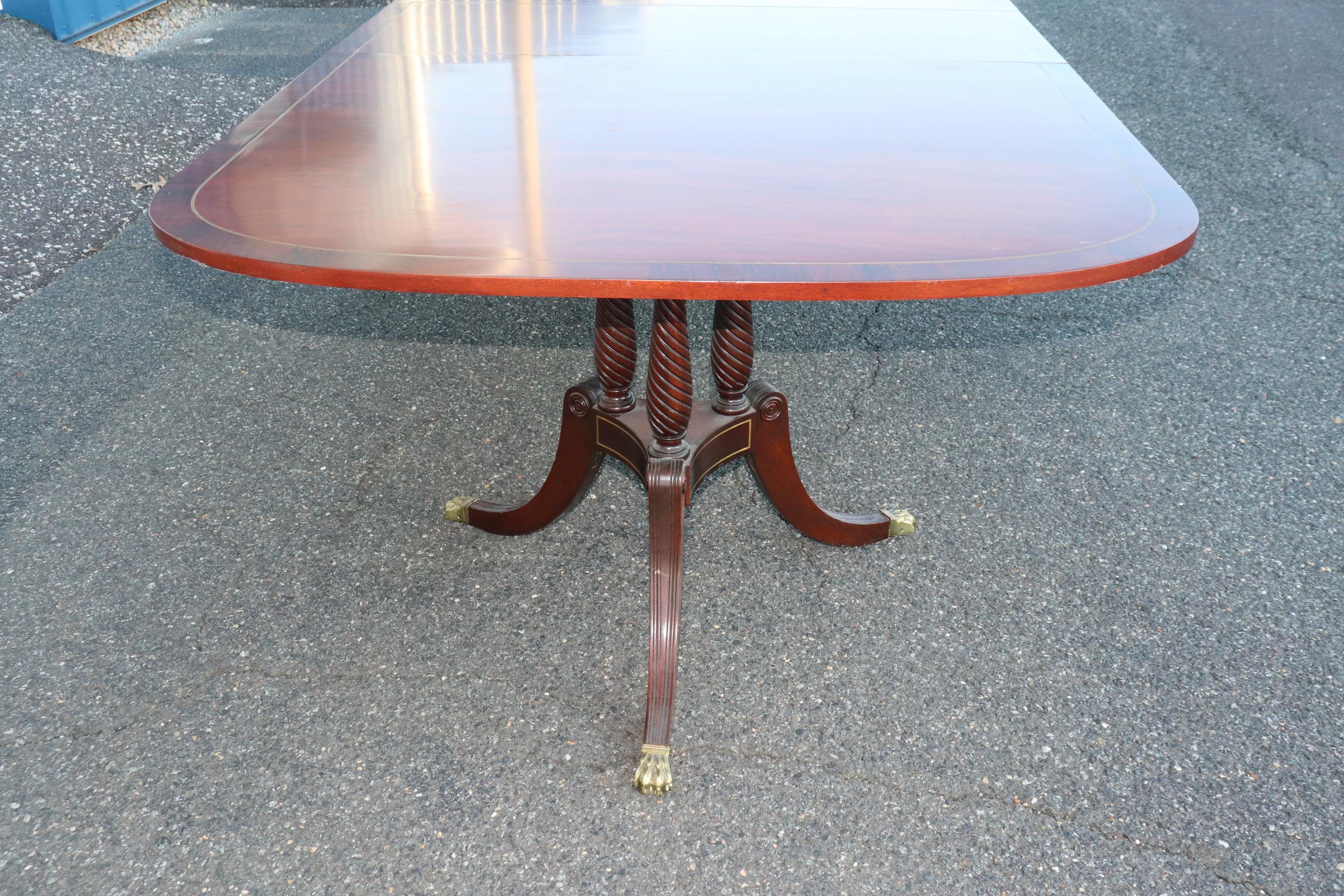Cette magnifique table de salle à manger présente un superbe bois de rose figuré avec des incrustations de laiton sur tout le périmètre de la table. Les bases sont également incrustées de laiton. L'état de la table est très bon pour son âge, et elle
