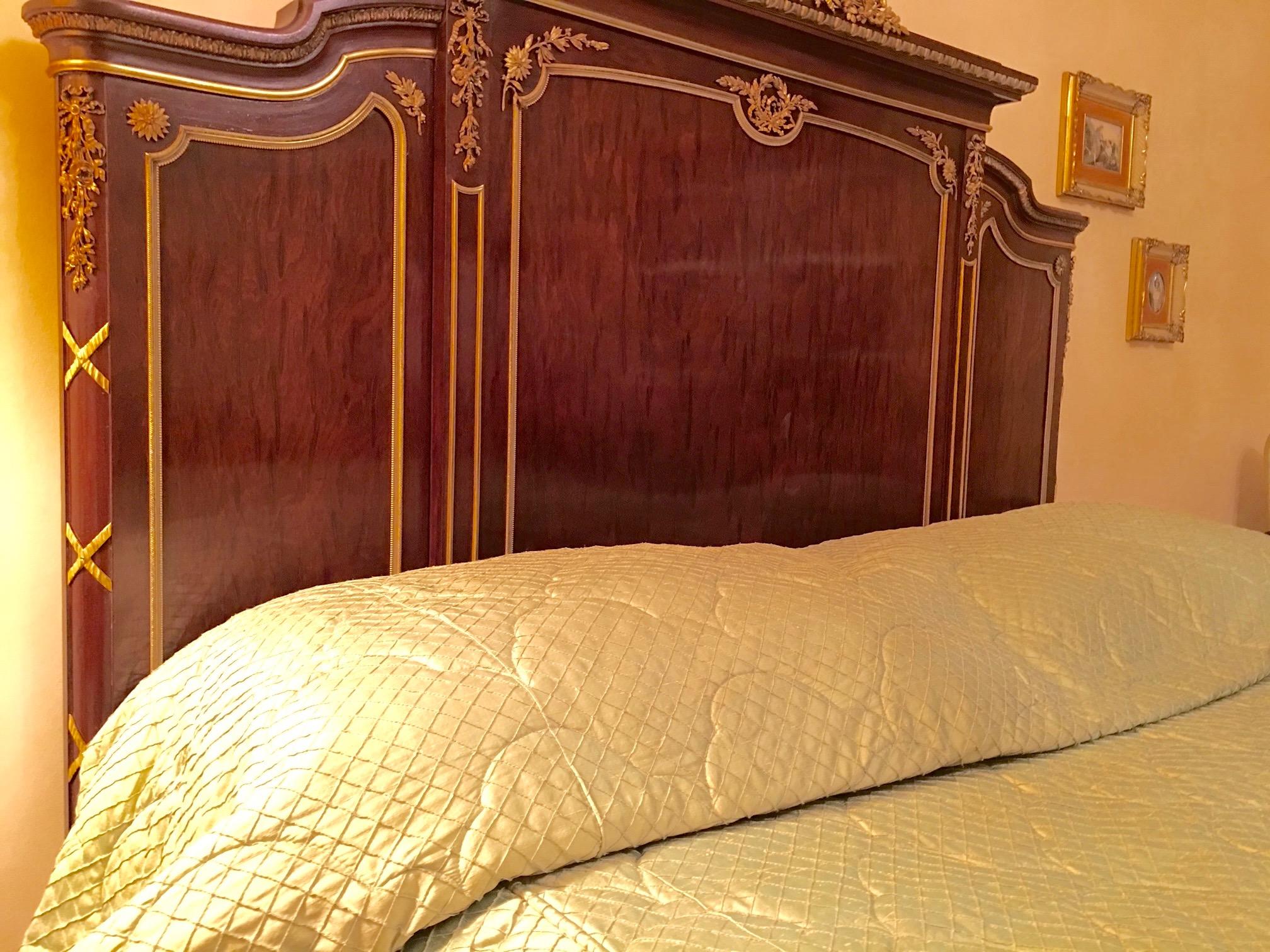Superior craftsmanship and elegant adornment characterize this exceptional European queen size bed by Francois Linke in the Marie Antoinette Revival style. The bed has a breakfront headboard with a gilt bronze floral garland, ribbon bow and floral