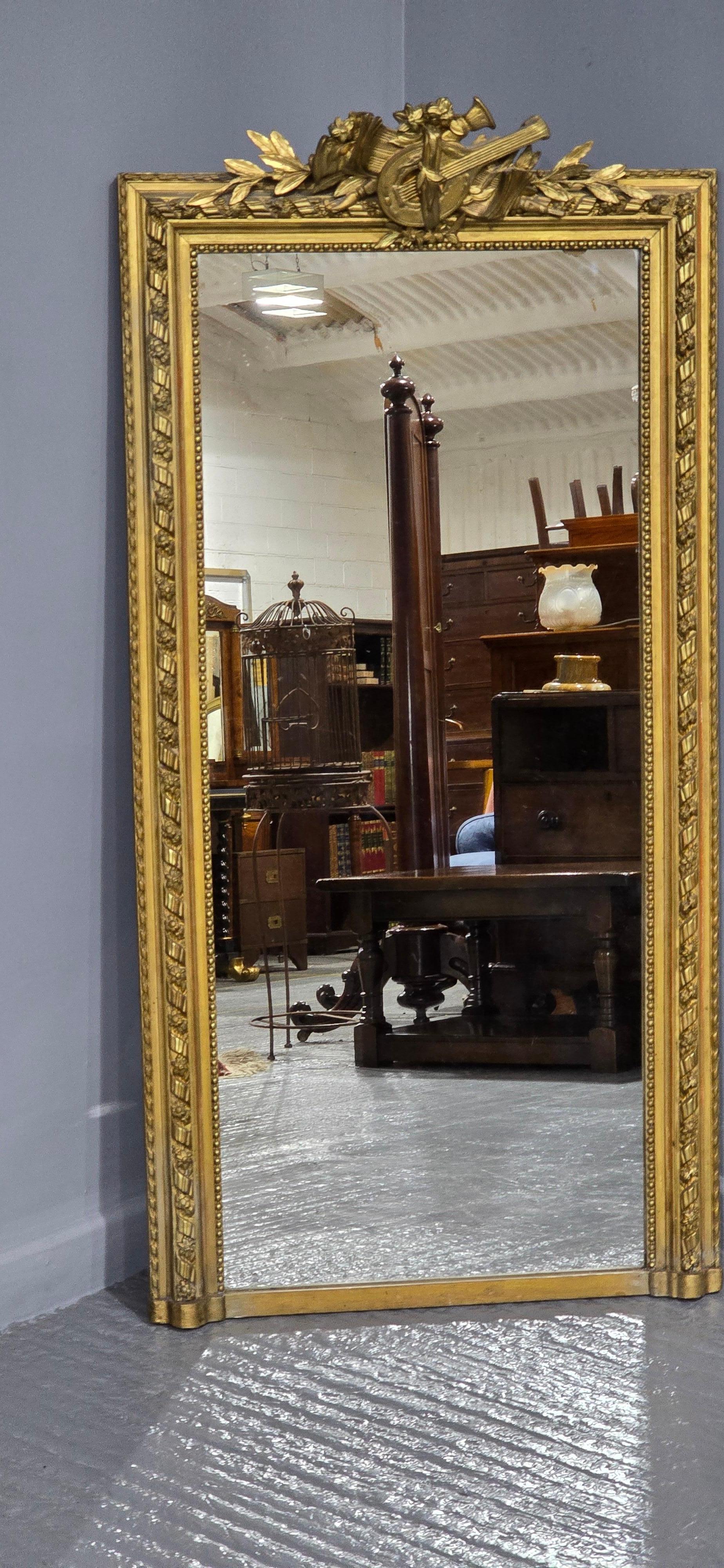 Superbe miroir français doré, instrument de musique et feuillage sur le dessus, vitre d'origine, en très bon état général.