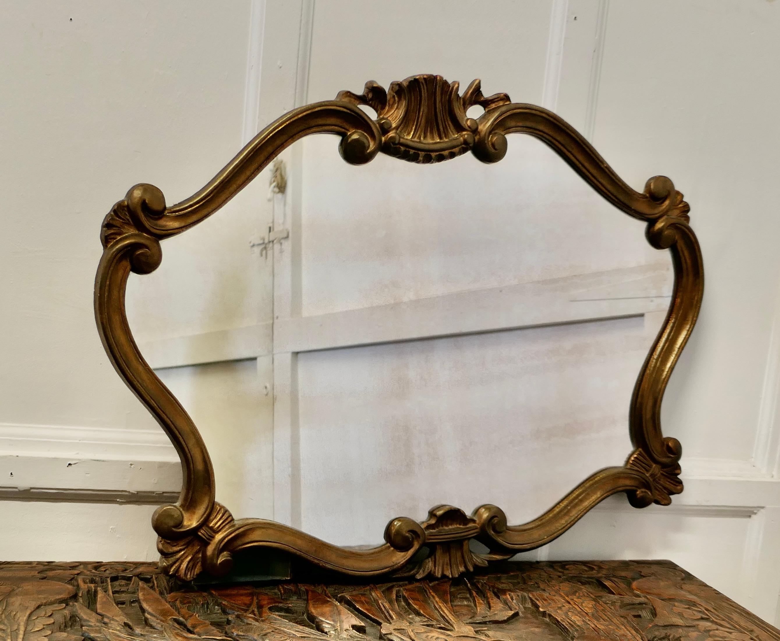 Superb French gilt scallop shaped overmantel 

This is a Striking piece it has a scroll shape with curved corners there is a carved shell decoration at the top with a wide border
The mirror is a lovely aged rich gold colour and would set off the