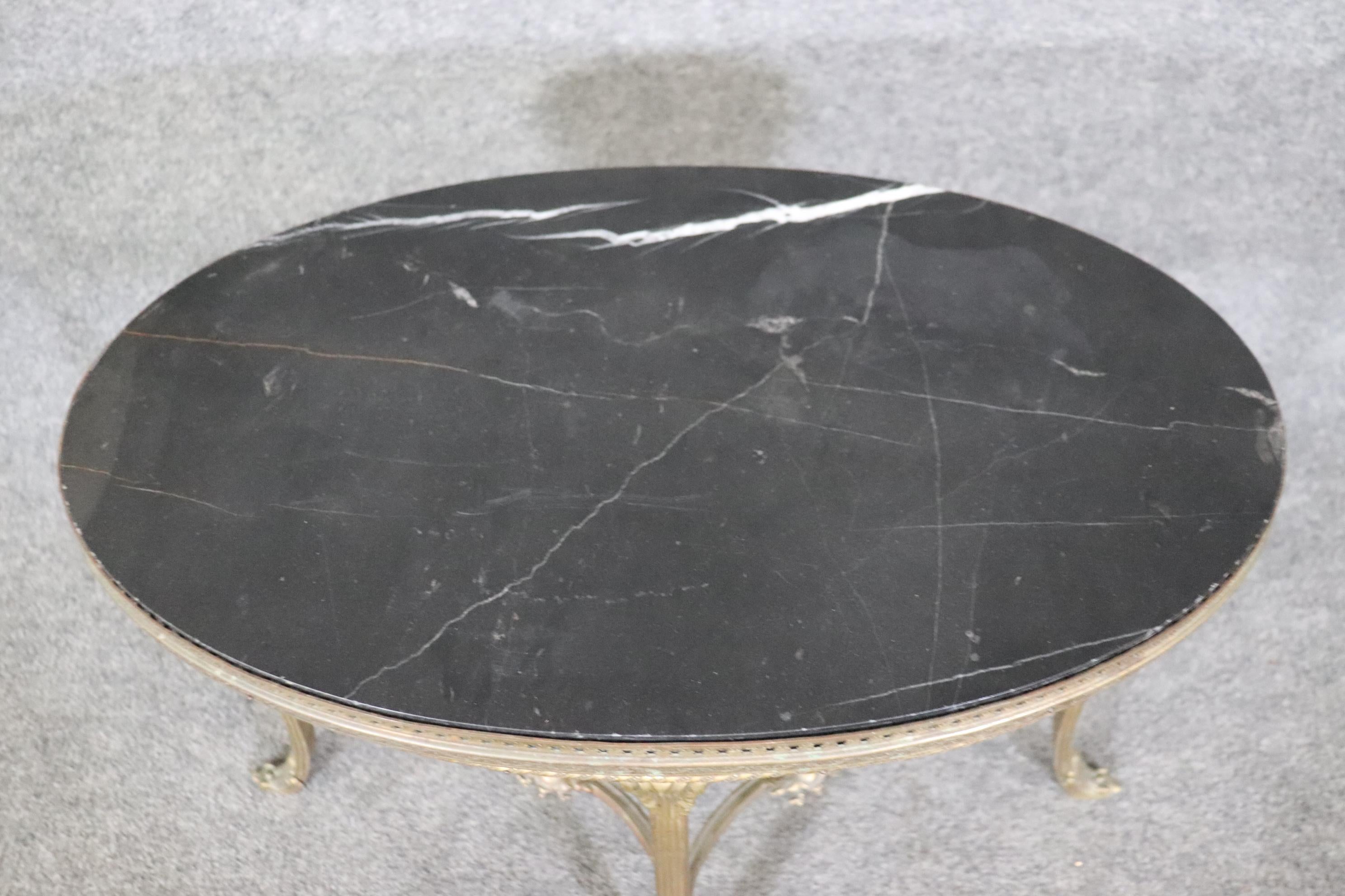 This is a superbly crafted coffee table of a relatively smaller scale but made of extremely durable cast brass or maybe bronze and a gorgeous black marble top. The table is in good antique condition and will show signs of age such as verdigris