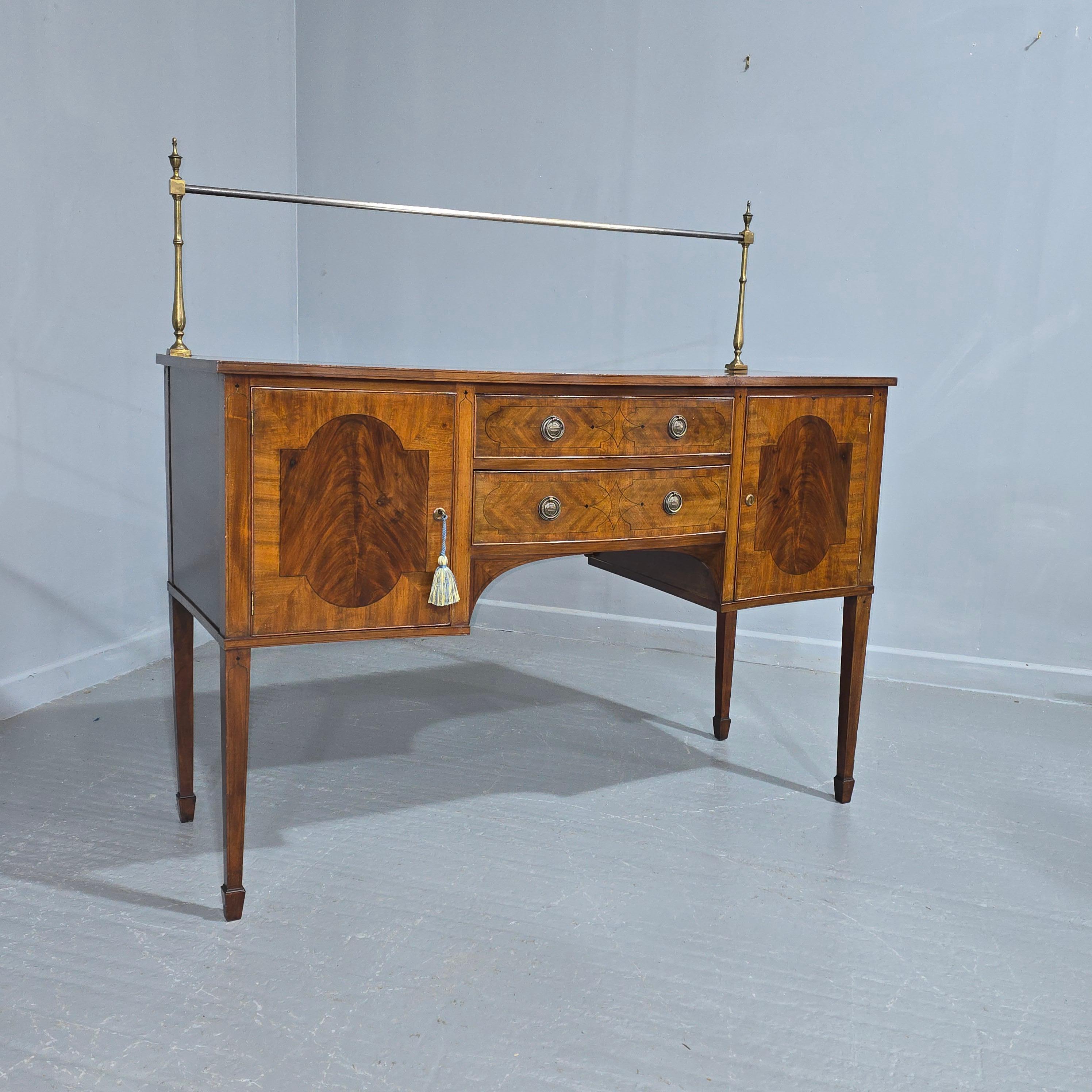 An early 19th century ebony line inlaid mahogany sideboard with a brass and steel rail back, the serpentine front with two central drawers and two opening doors with working keys,  excellent colour and condition.

37