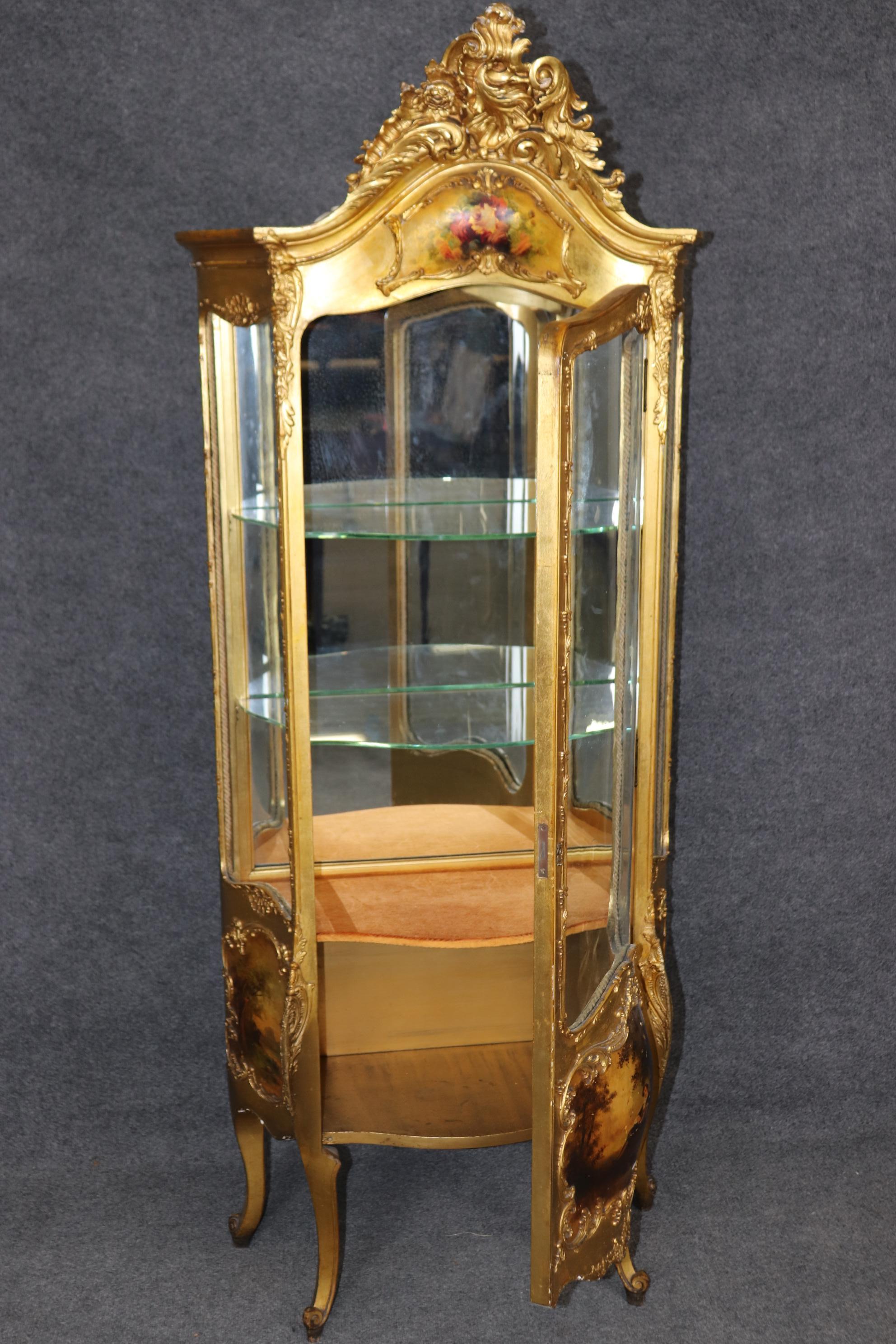 This is a gorgeous and very luminous gilded carved French vitrine. Done in the Vernis Martin style, the vitrine is painted with a courtship scene and beautifully finished in bright genuine 23kt gold leaf. This is a rare form of vitrine with some of