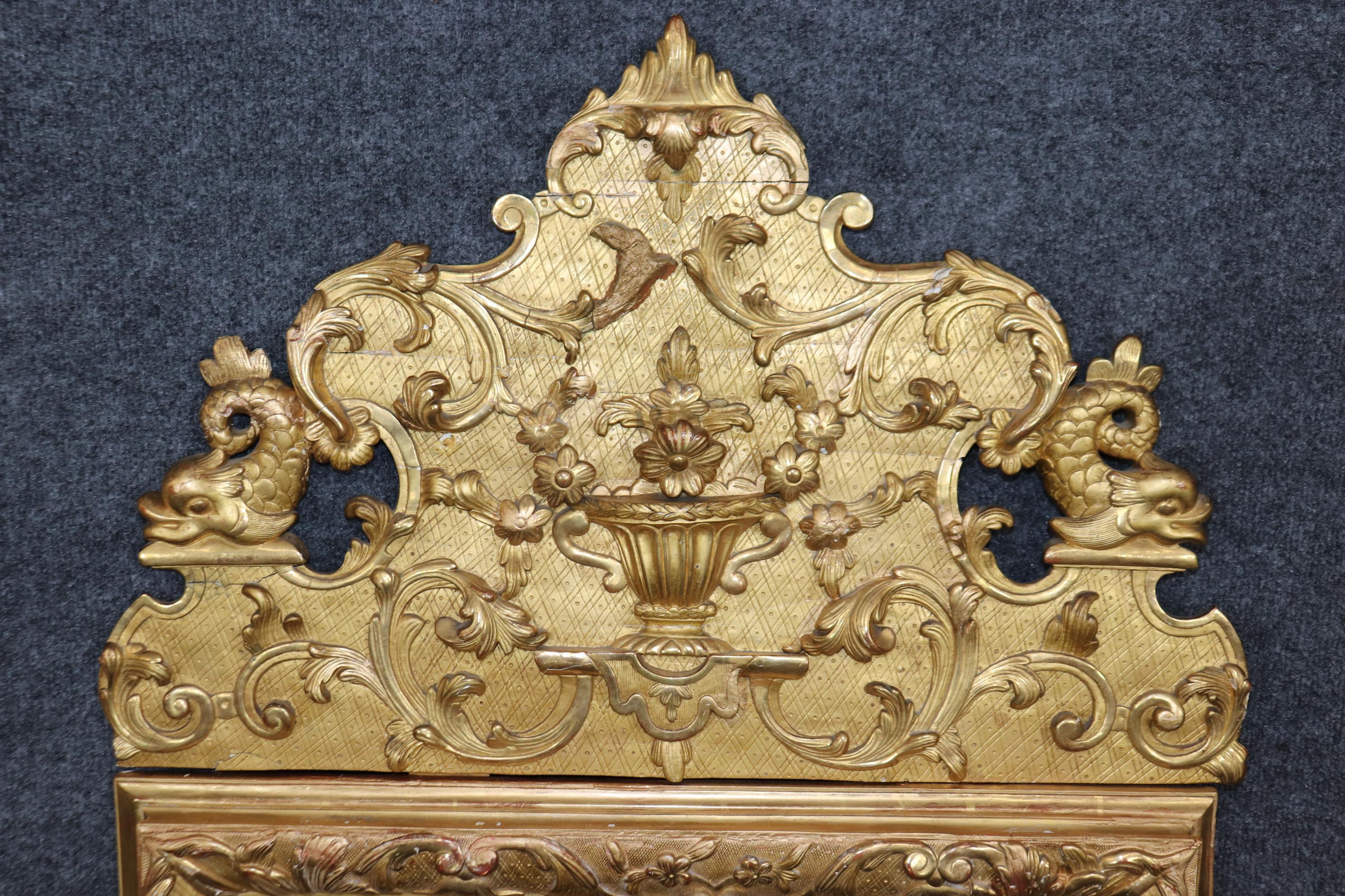 This is truly superb mirror with the brightest gilding and gorgeous carved details of flowers and various elements. There is a partial manufacturer signature on the back. The mirror plate is antique and has signs of age and patina including spots