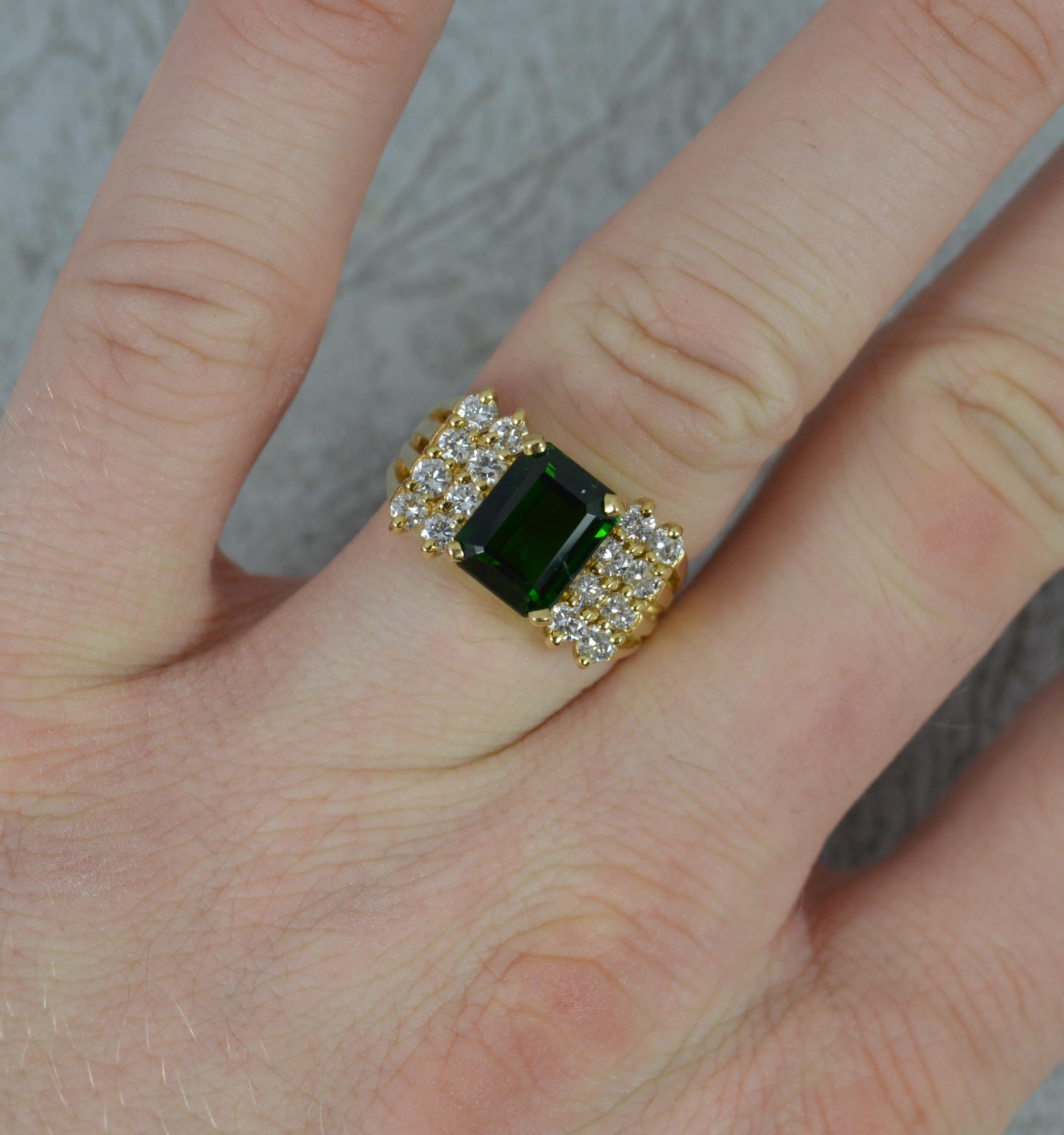A superb contemporary cluster ring.
Solid 18 carat yellow gold example. Well made substantial piece.
Designed with a large emerald cut green tourmaline to centre in four claw setting. 7mm x 9mm approx.
To each side are two columns of four round
