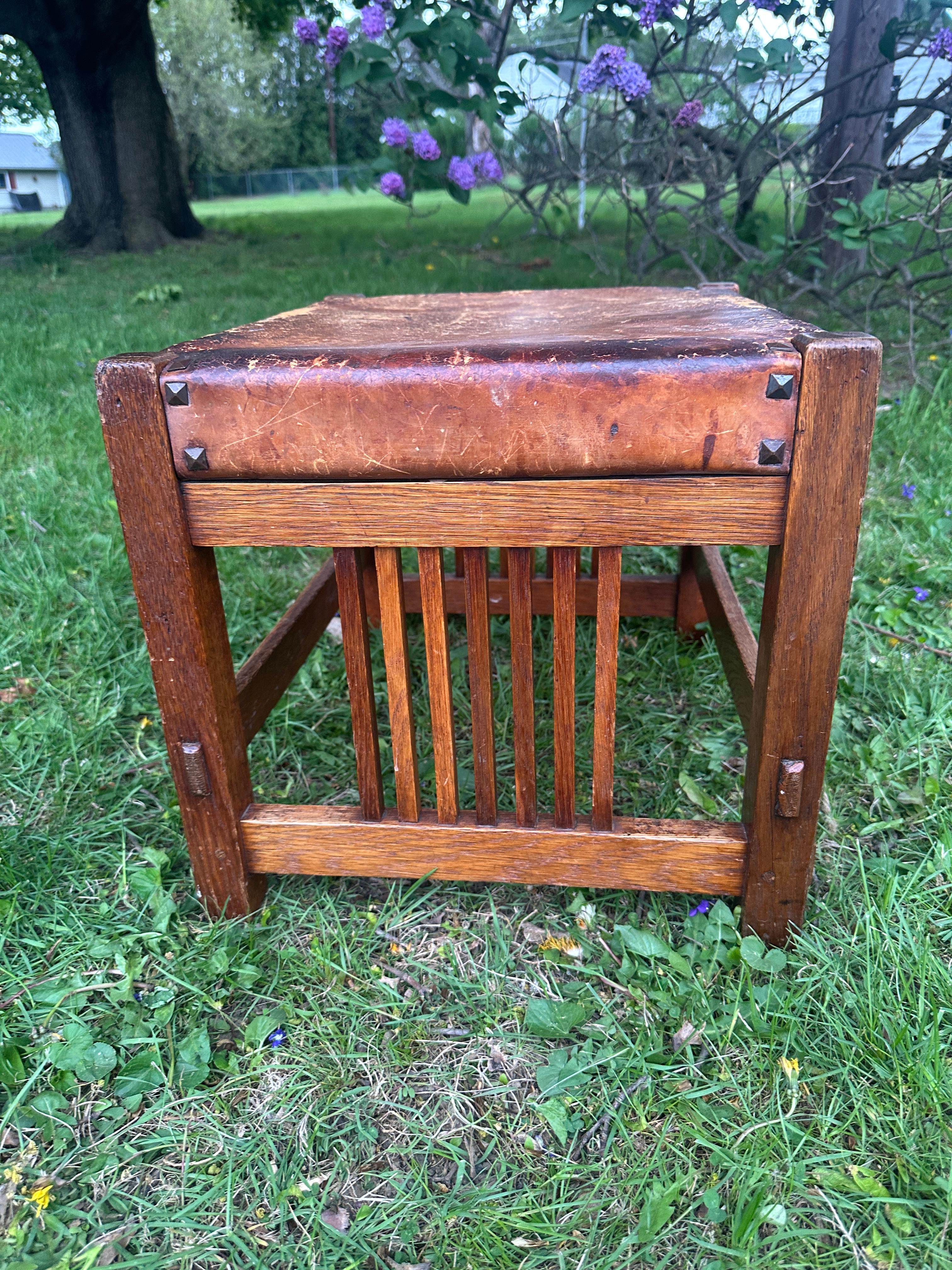 Dies ist ein großer Gustav Stickley Fußhocker aus den frühen 1900er Jahren in sehr gutem Zustand. Der Hocker aus Eichenholz hat an zwei Seiten Spindeln, wie abgebildet. Das Stück hat seine ursprüngliche Oberfläche mit etwas Überzug. Es hat die