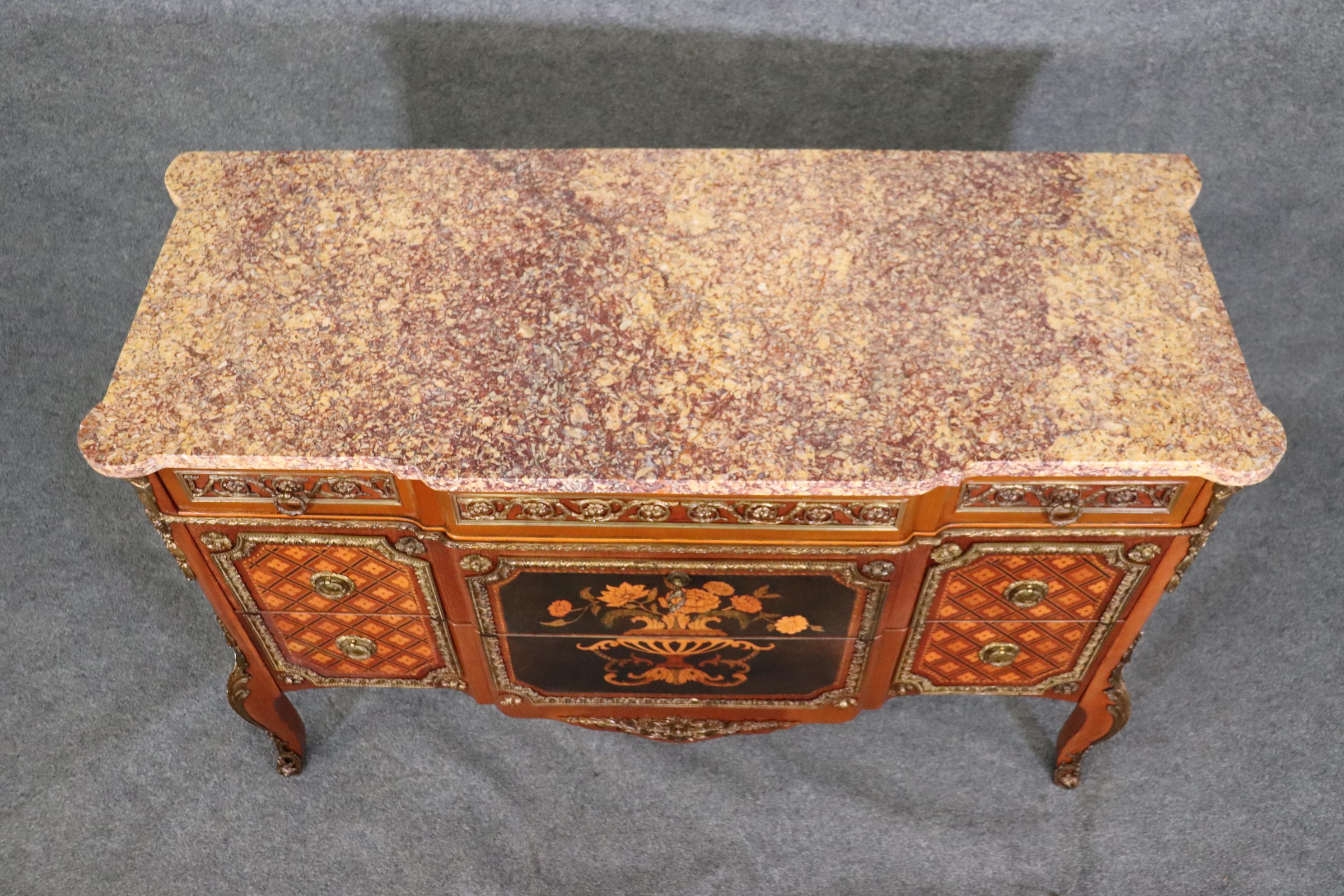 This is a truly gorgeous marble top inlaid marquetry commode made in France during the 1940s era and has a wonderful slab of purple lace marble and incredible intracate inlay and bronze. The commode is in good condition with minor signs of age and
