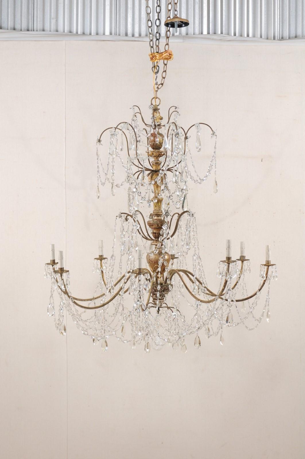 A generously-sized Italian crystal and giltwood column chandelier from the early 20th century. This antique chandelier from Italy, with a height of nearly 4.5 feet tall, features an elegantly carved wood central column with original gilt finish,
