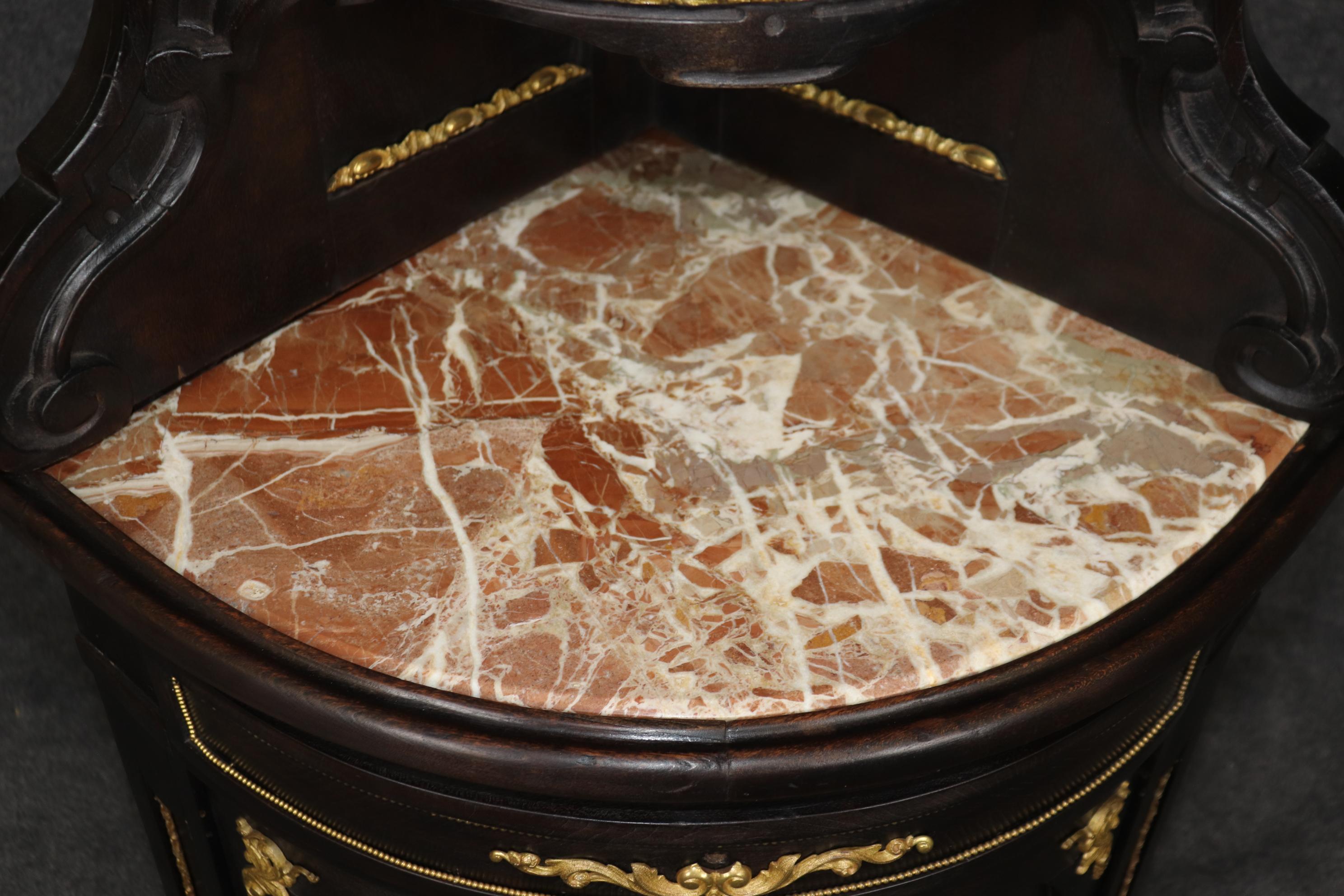 Si tratta di un mobile ad angolo molto particolare, con finiture in bronzo ormolu e oro dorato e un piano cilindrico dal design superbo, ornato da un piano in marmo stile breccia color corallo. Il mobile ha bisogno di una piccola riparazione alla
