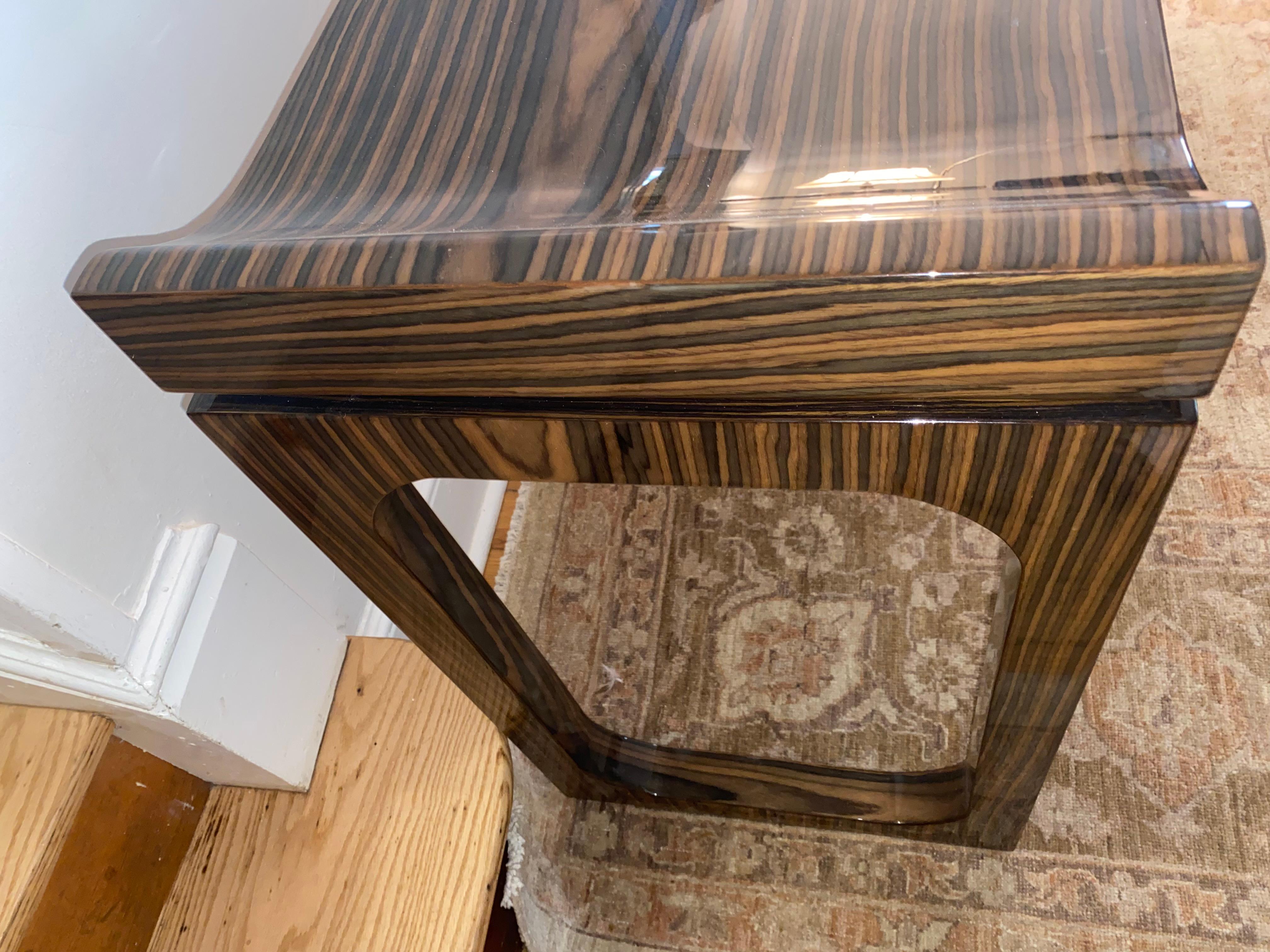 Eye catching superb laquered console having gorgeously grained macassar veneer wood.  Console curves up at each side and bookend legs with stretchers add to the silhouette.