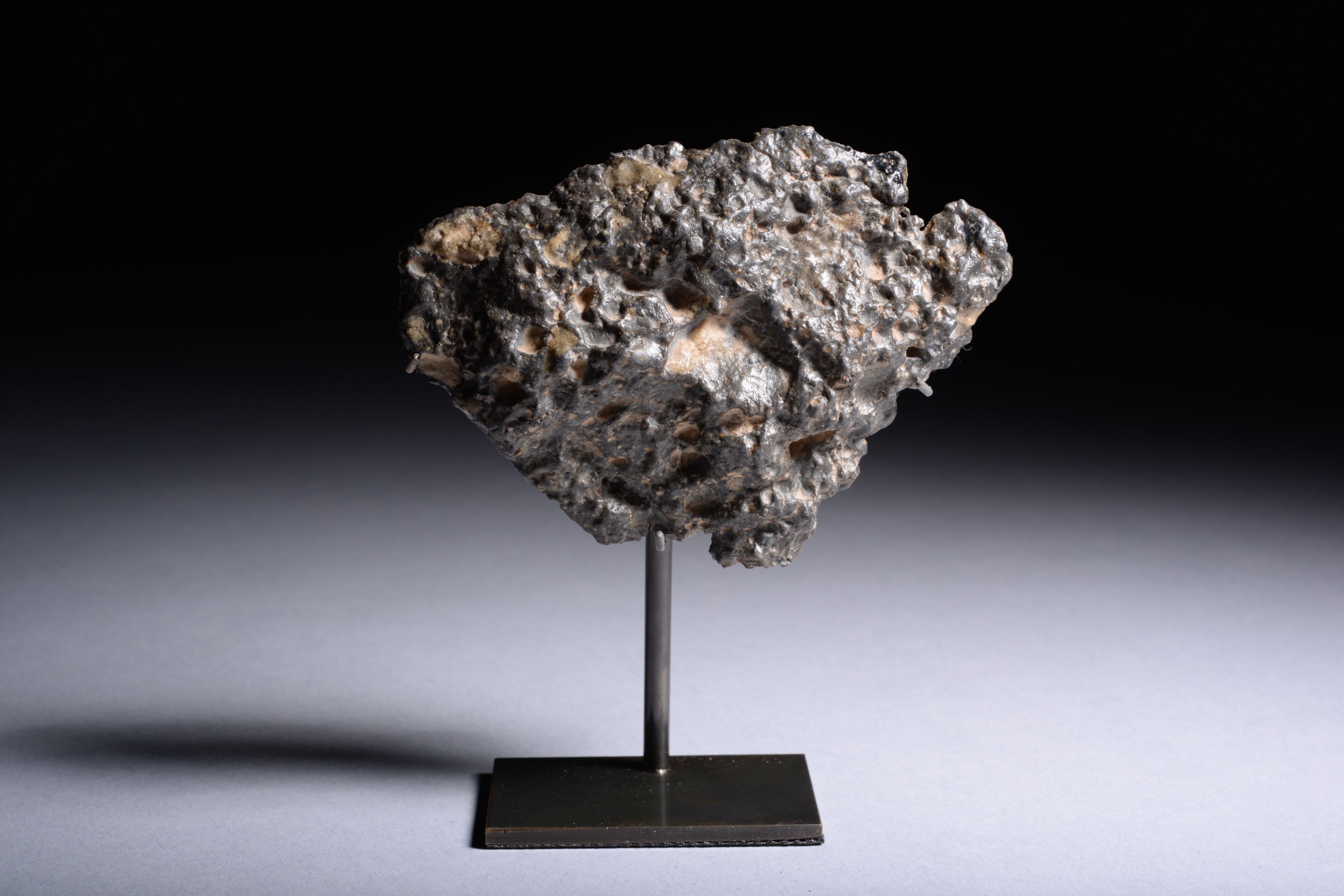 A beautiful fragment from a lunar meteorite, among the rarest of all geological finds. This specimen belongs to NWA 11303, a feldspathic regolith breccia which formed when the shock wave caused by an asteroid impact turned the fine-grained soil (or