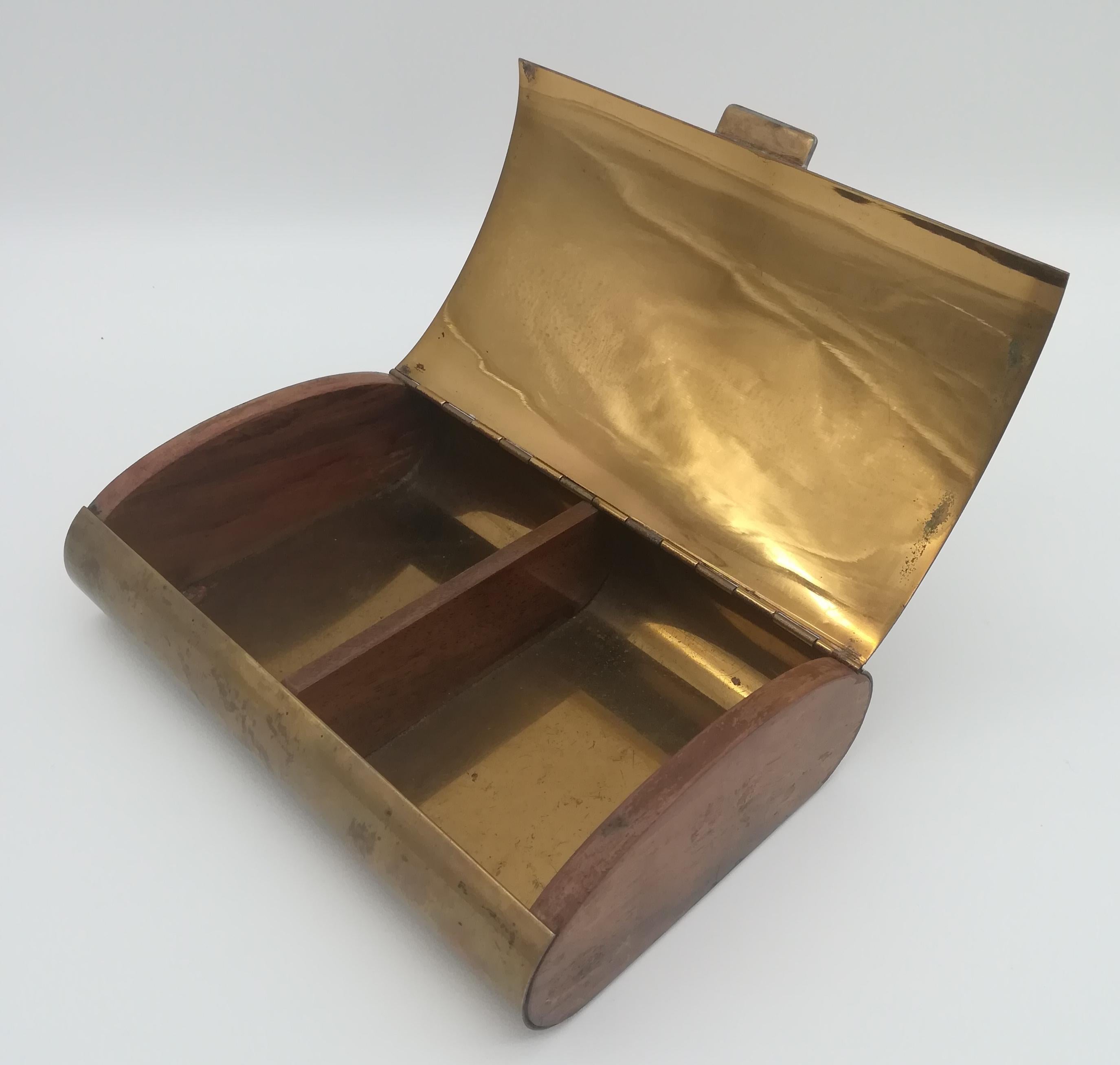 This lovely brass and wooden cigarette box, designed by Carl Auböck, shows a beautiful guilloche top surface. The brass shows fine patina, enriched by the contrast of the wooden sides of the box. The bottom surface is slightly tarnished, the