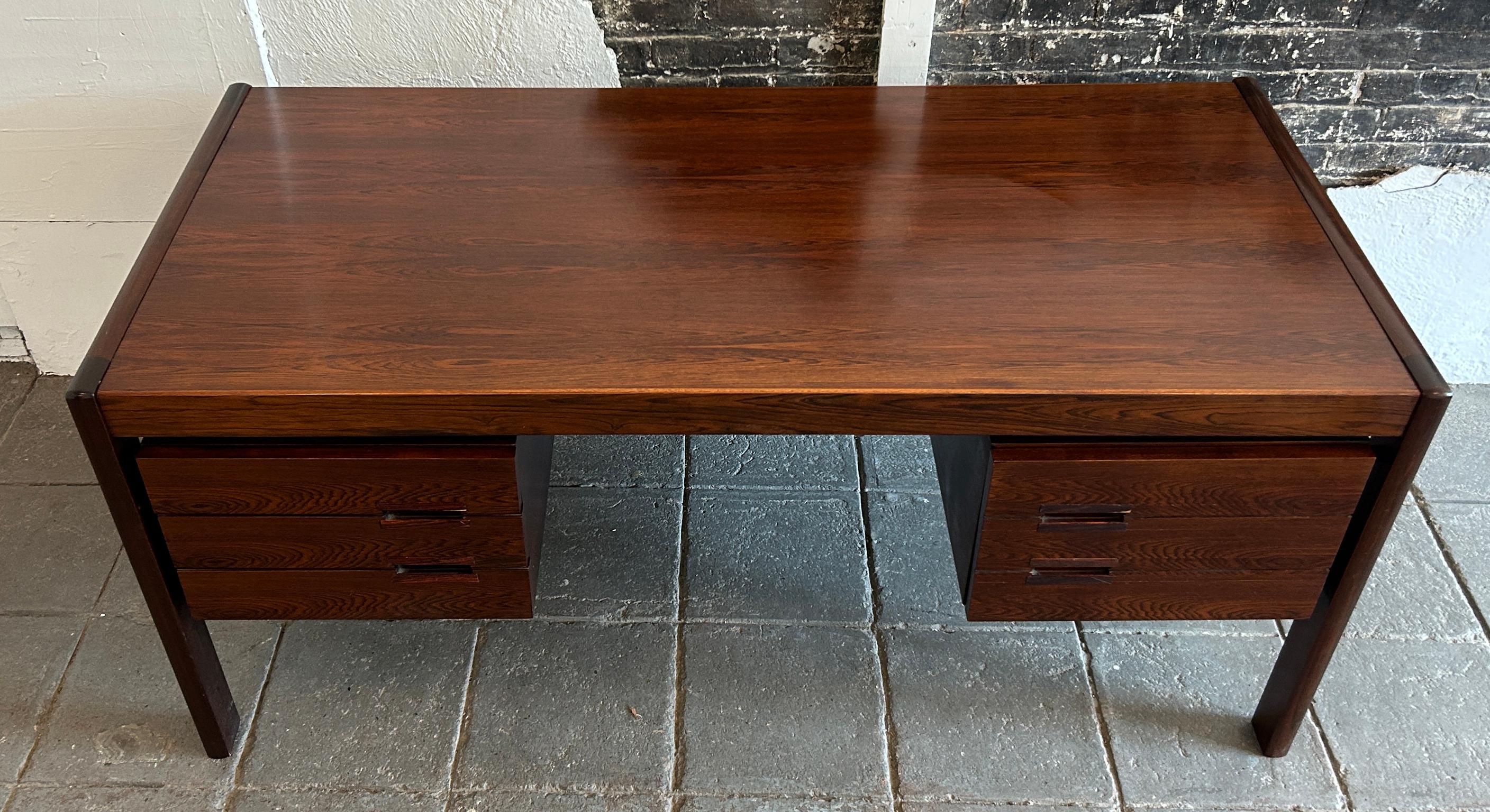 Superb Mid Century Danish Modern Rosewood Floating Desk by Dyrlund. All dark rosewood desk with 3 drawers on the left and 1 large drawer on the right for files etc. The front side of the desk is finished in rosewood and has a center bookshelf. This