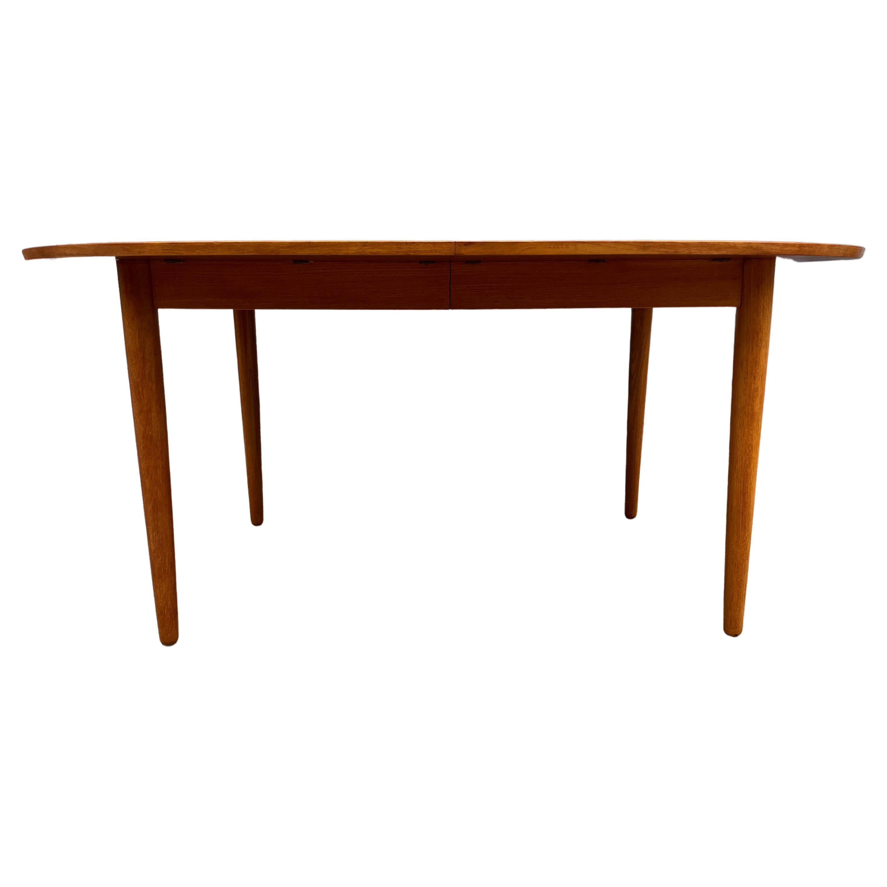 Stunning Mid century Teak oval Danish Modern extension dining table with (2) leaves. This table has Solid teak tapered wood legs. In the Style of Arne Vodder. This table is in Great vintage condition. Superb construction and both leaves match the