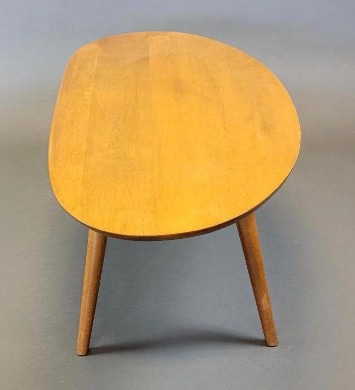 A wonderful and playful oval shaped coffee table with a raised edge. Made from solid maple. Designed by the famous architect Russel Wright. In original condition showing normal wear for use. Blonde maple finish. Located in Brooklyn NYC.