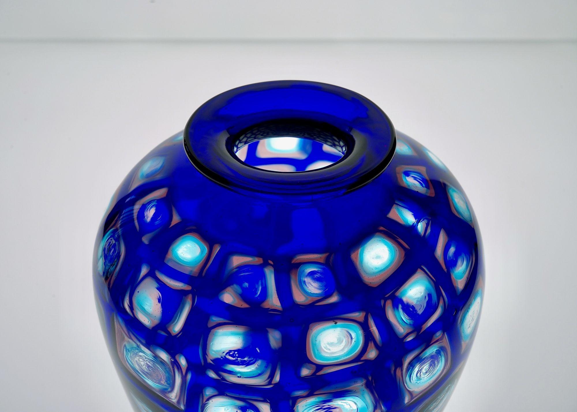 Murano glass cachepot vase with square murrine with aqua mare, amethyst and cobalt blue color play.

The cobalt blue outside the murrine connects to the adjacent ones creating an web. The pale colored inside in light amethyst and aquamarine allows
