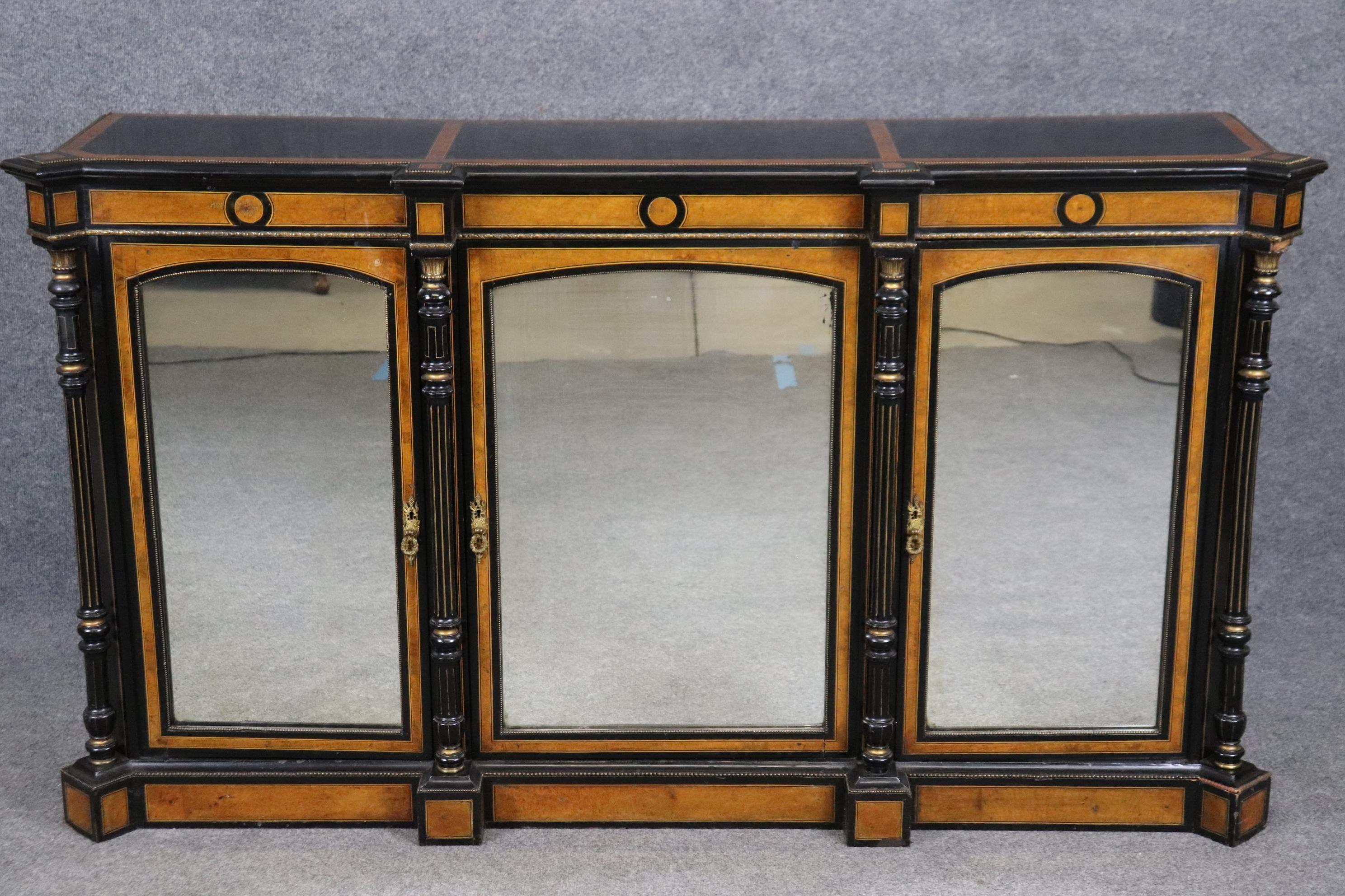 This a gorgeous Napoleonic style ebonized case and burled walnut sideboard or credenza. The sideboard features a beautiful contrast between light and dark woods and is in good antique condition with clear mirrors. Measures 40.75 tall x 72.5 wide x
