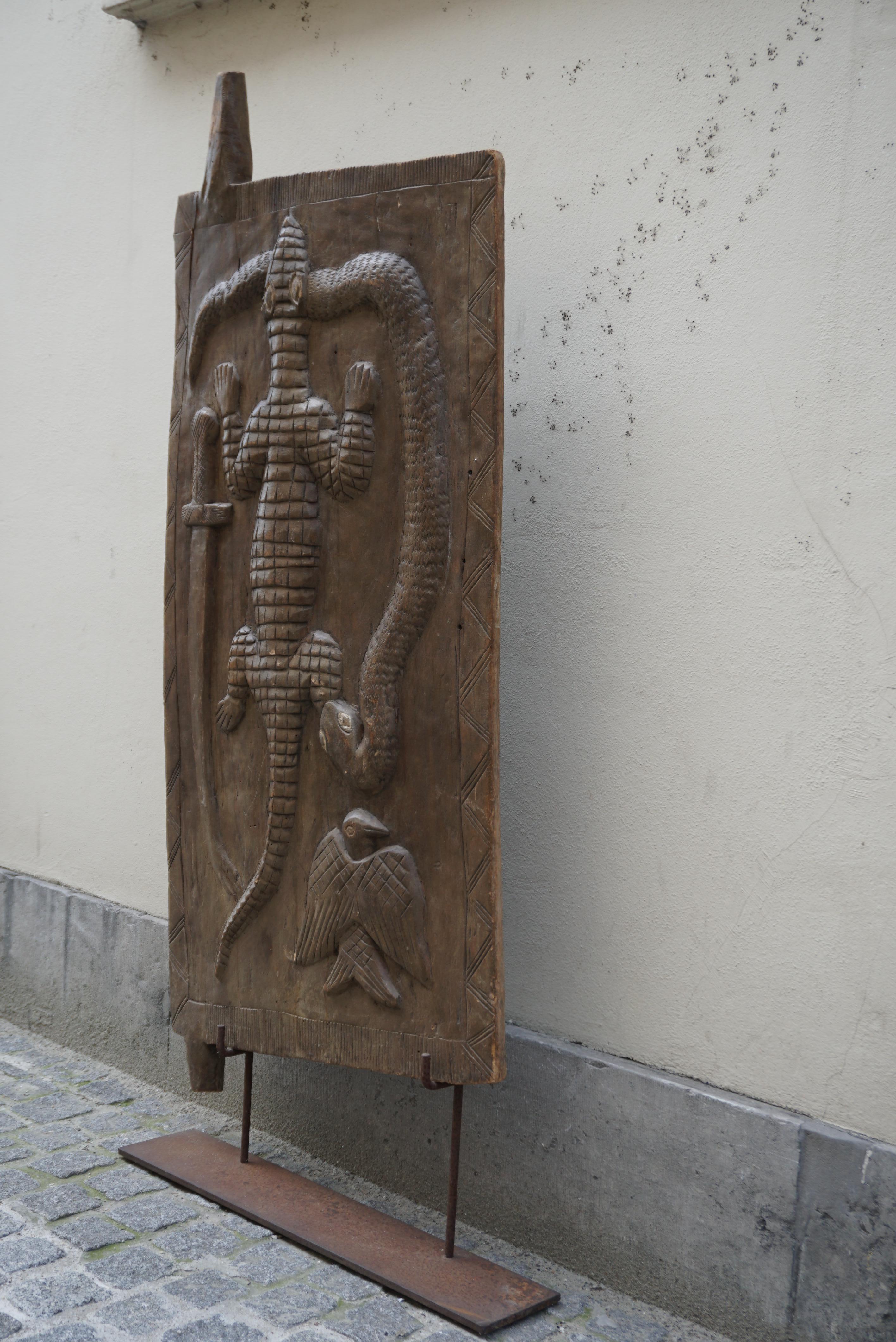Old wooden hut door from Cameroon, decorated with carved crocodile, bird, snake and a knife within geometric ornament in the traditional ethnic style. 
Superb old door African sculpture.

Dimensions of the door without the iron frame.
Width 28.7