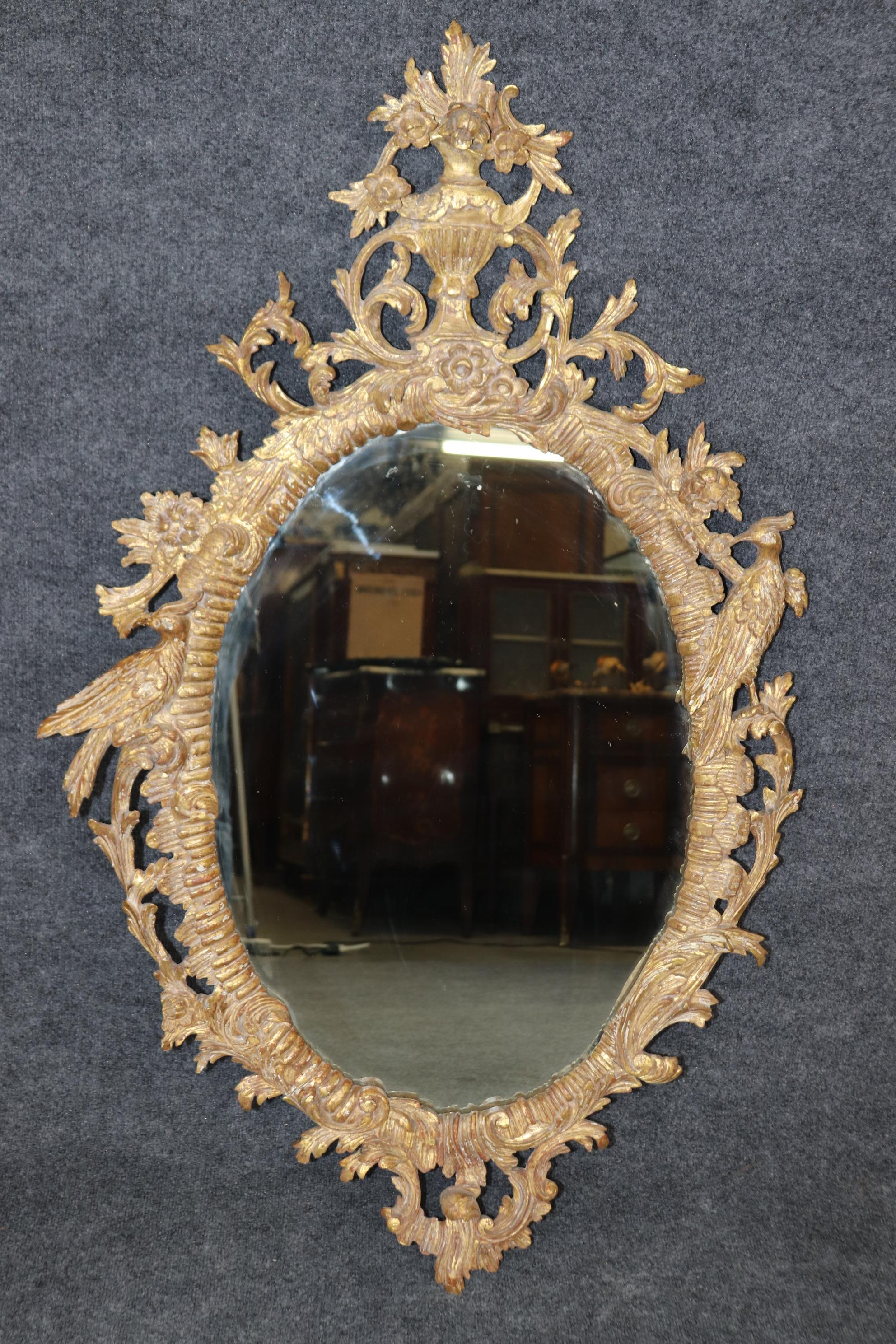 This is a gorgeous pair of antique English carved wall mirrors with carved birds and a great antique distressed gilt wood finish. They are decadent and of superb quality. Measures 49 tall x 29.75 wide x 4.5 deep. Dates to the 1910-20s era. 