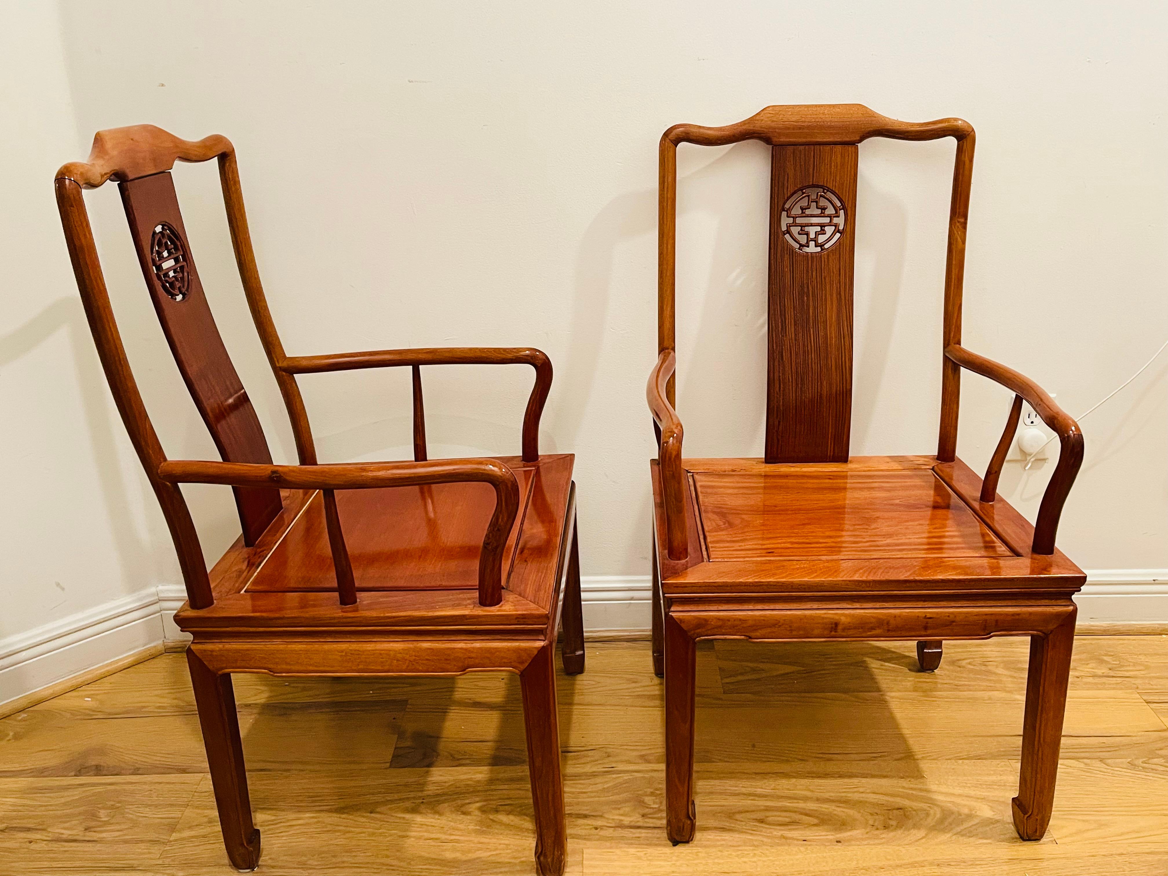 Coppia di superbe sedie cinesi vintage intagliate a mano in legno di teak con simbolo di longevità sullo schienale. Legno di teak splendidamente lucidato in un colore ambrato. Poltrone dalle proporzioni eleganti. Cuscini di seduta disponibili.