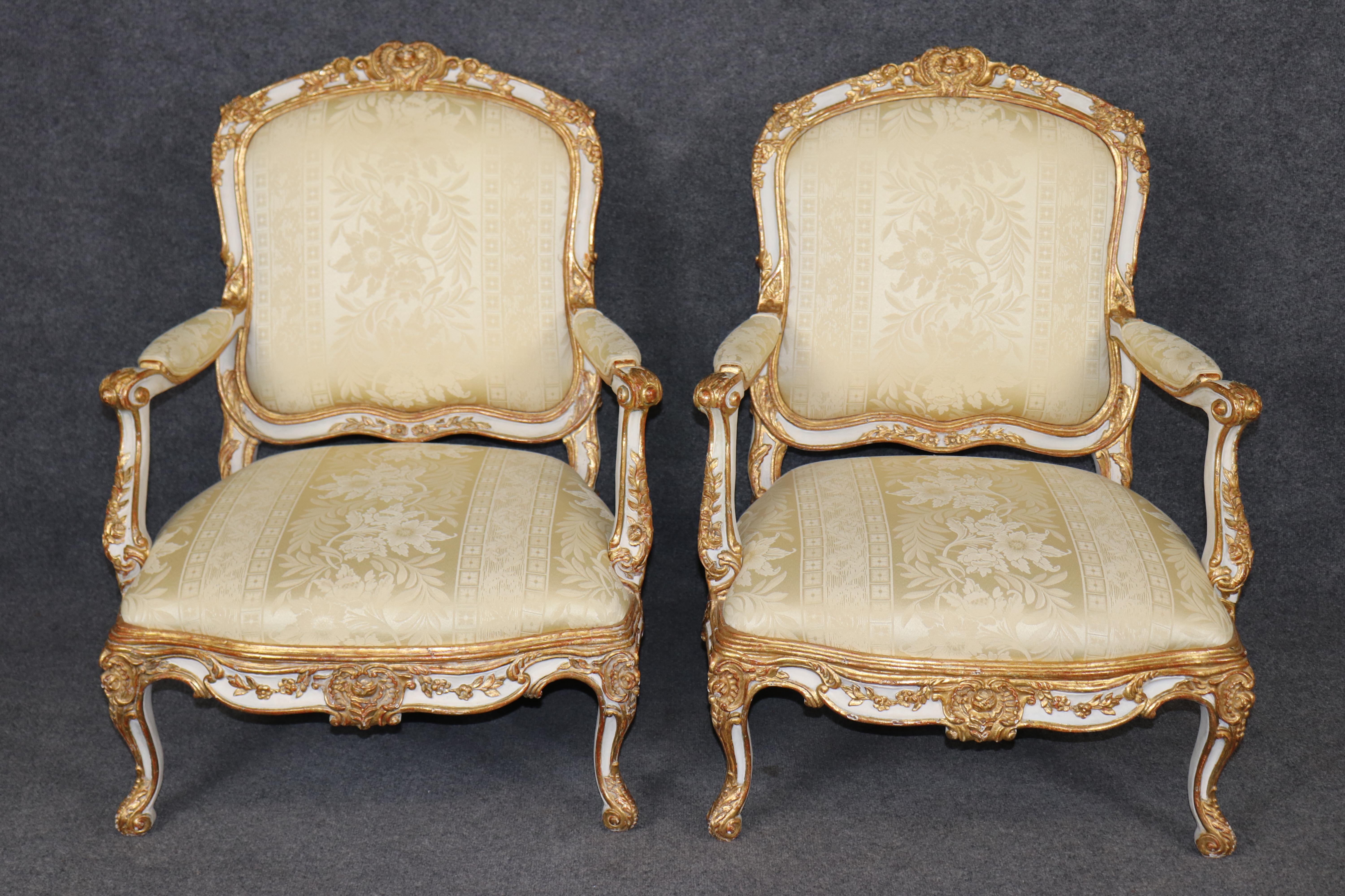 This is an exceptional and extremely rare and beautiful pair of over-sized armchairs in the Louis XV style. They are from the 1870s era and are ornately carved with Italian red clay bole underlining the genuine gold leaf. The upholstery is still