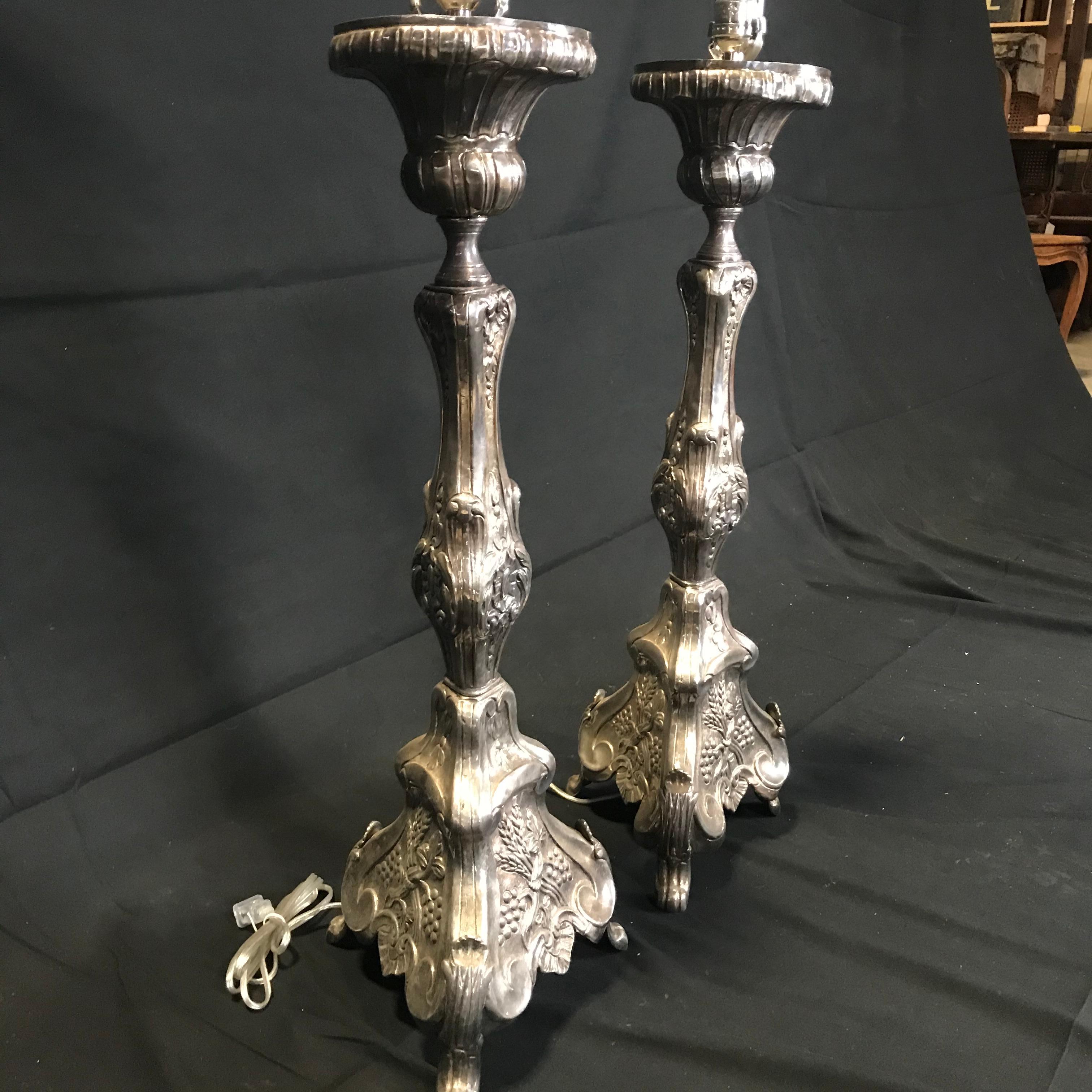 Superb pair of 19th century French silvered bronze altar sticks made into lamps, having finely cast detailing. Each candlestick features a central shaft adorned in a seashell motif, fluted sides and richly adorned tripod base with foliage motifs