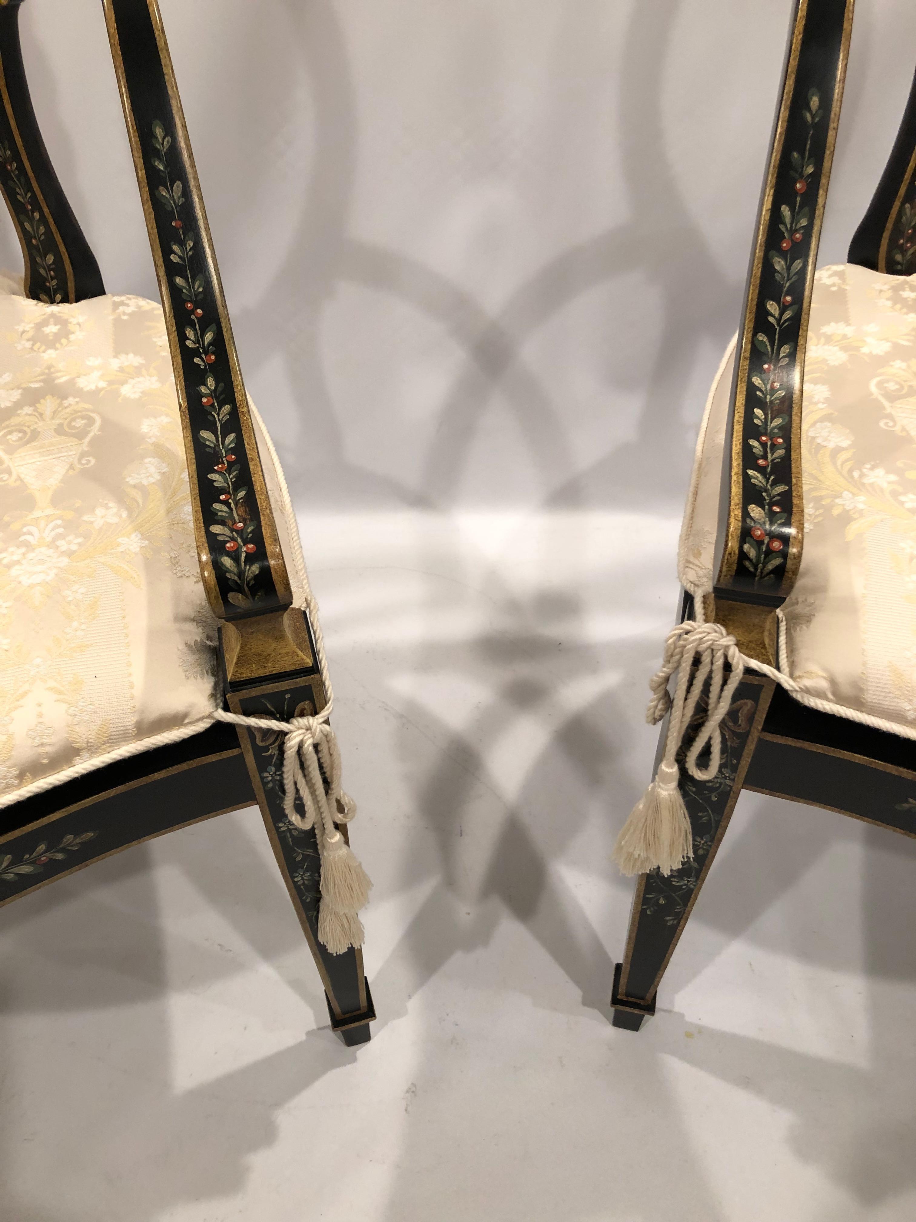 Lovely pair of elegant Adam style hand painted wood armchairs having black background with gold details and red and green berry like decoration. Seats are caned with custom off white cushions.
Measures: Arm height 28.5.
