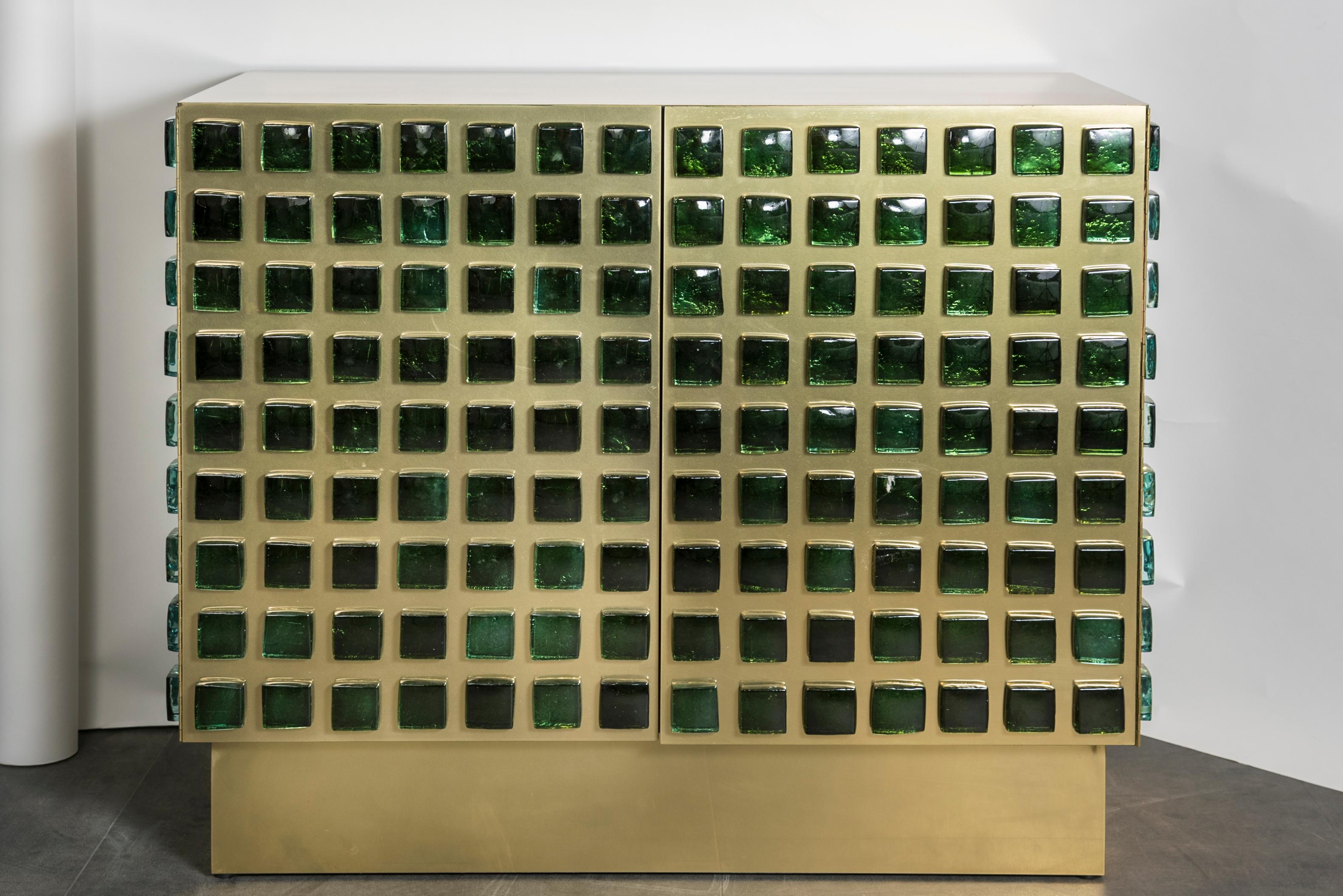 This pair of cabinets are in wood covered with brass, and decorated with molted green glass squares. Unique and contemporary creation by Studio Glustin, France, 2019.