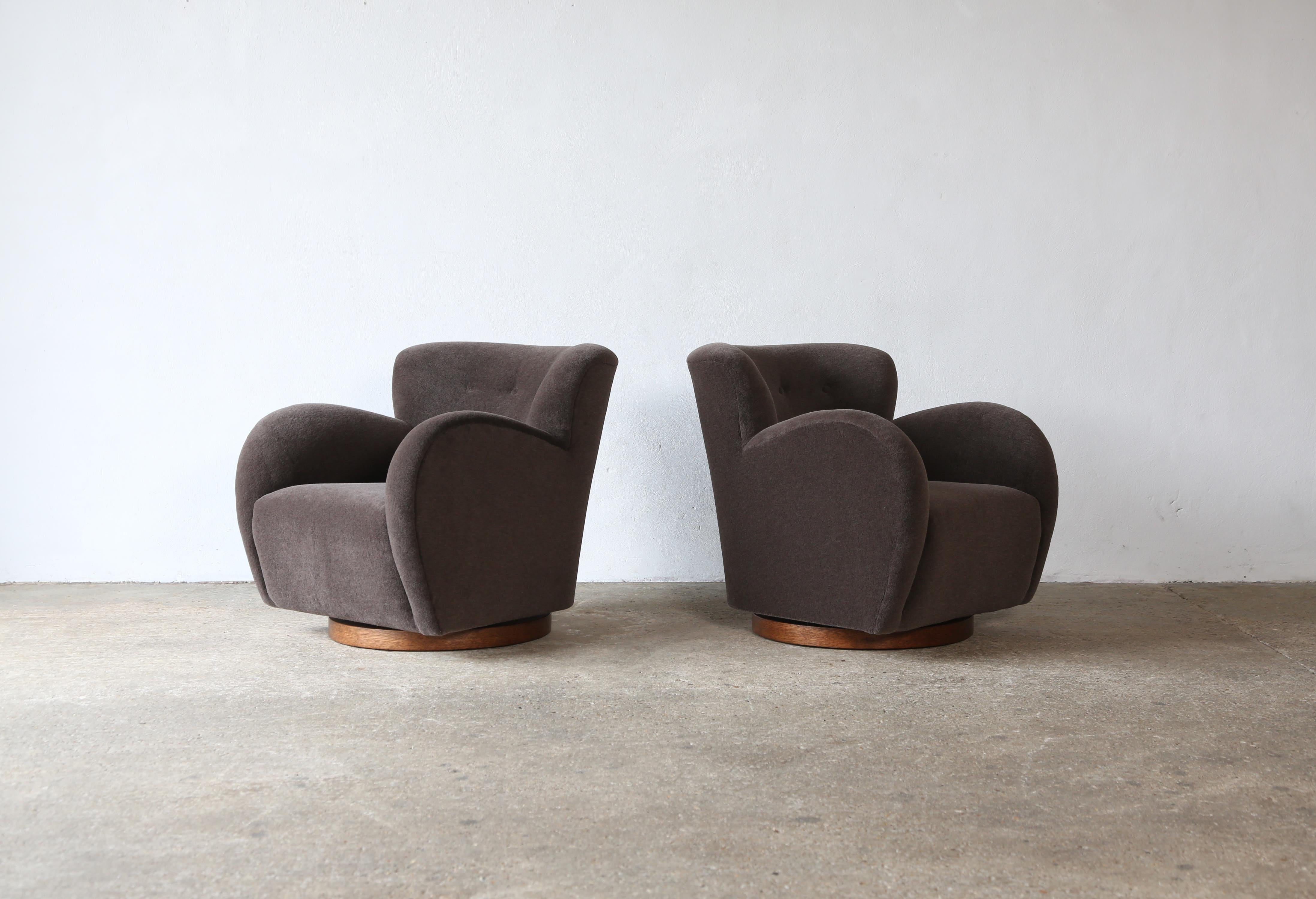 A superb pair of modern round arm swivel armchairs. Beech frames, sprung seat and newly upholstered in a premium, soft, taupe pure alpaca wool fabric, on a wooden base.   Swivels 90 degrees in each direction with return mechanism.   Handmade in