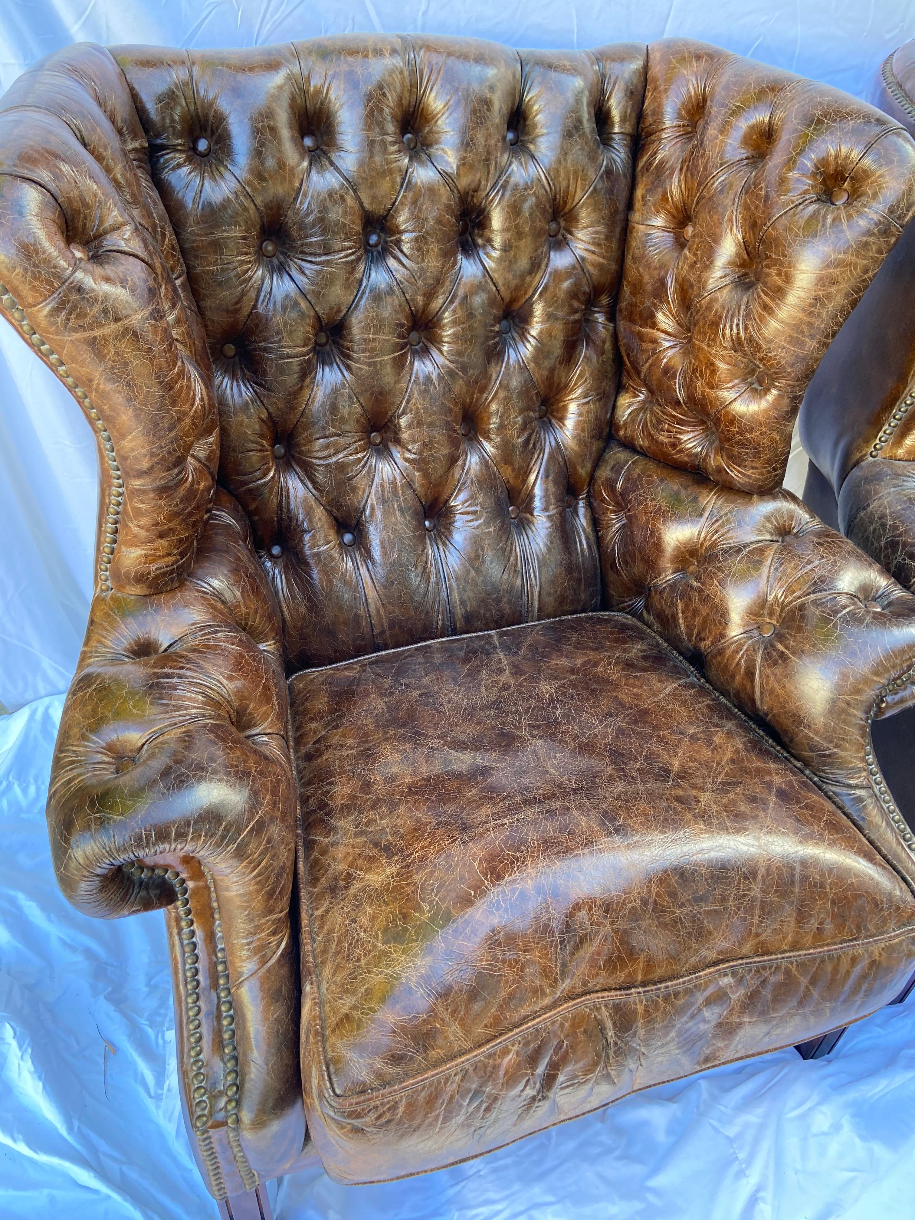 Superb pair of vintage leather wing-back tufted club chairs. Measures: 42” tall, 38” wide, 32” deep, 19 seat high.