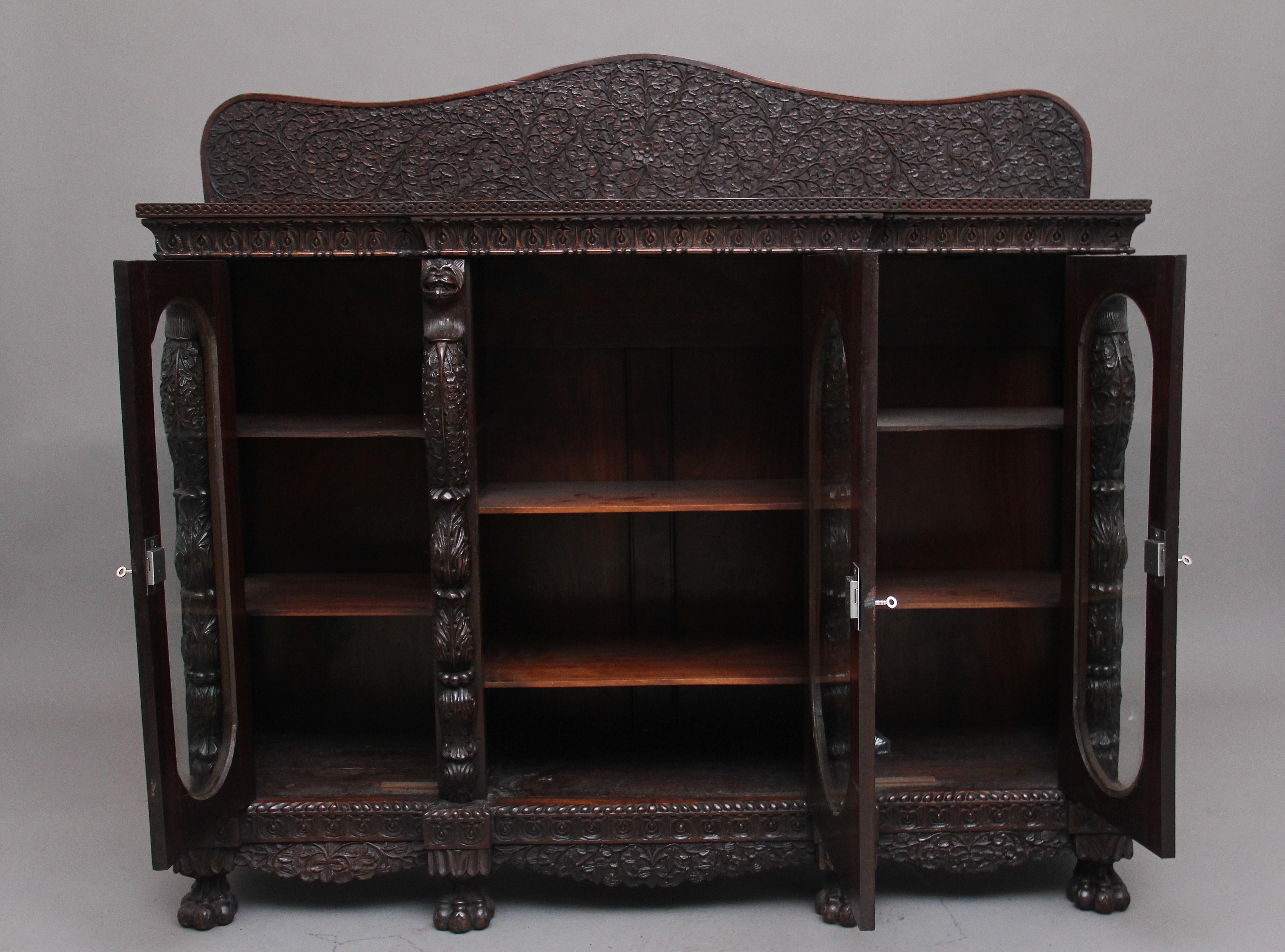 A fabulous quality 19th century Burmese carved breakfront three door cabinet, profusely carved all over with pierced and carved flowers, foliage and vines, having a nice figured top with a shaped back carved and pierced with further foliage and