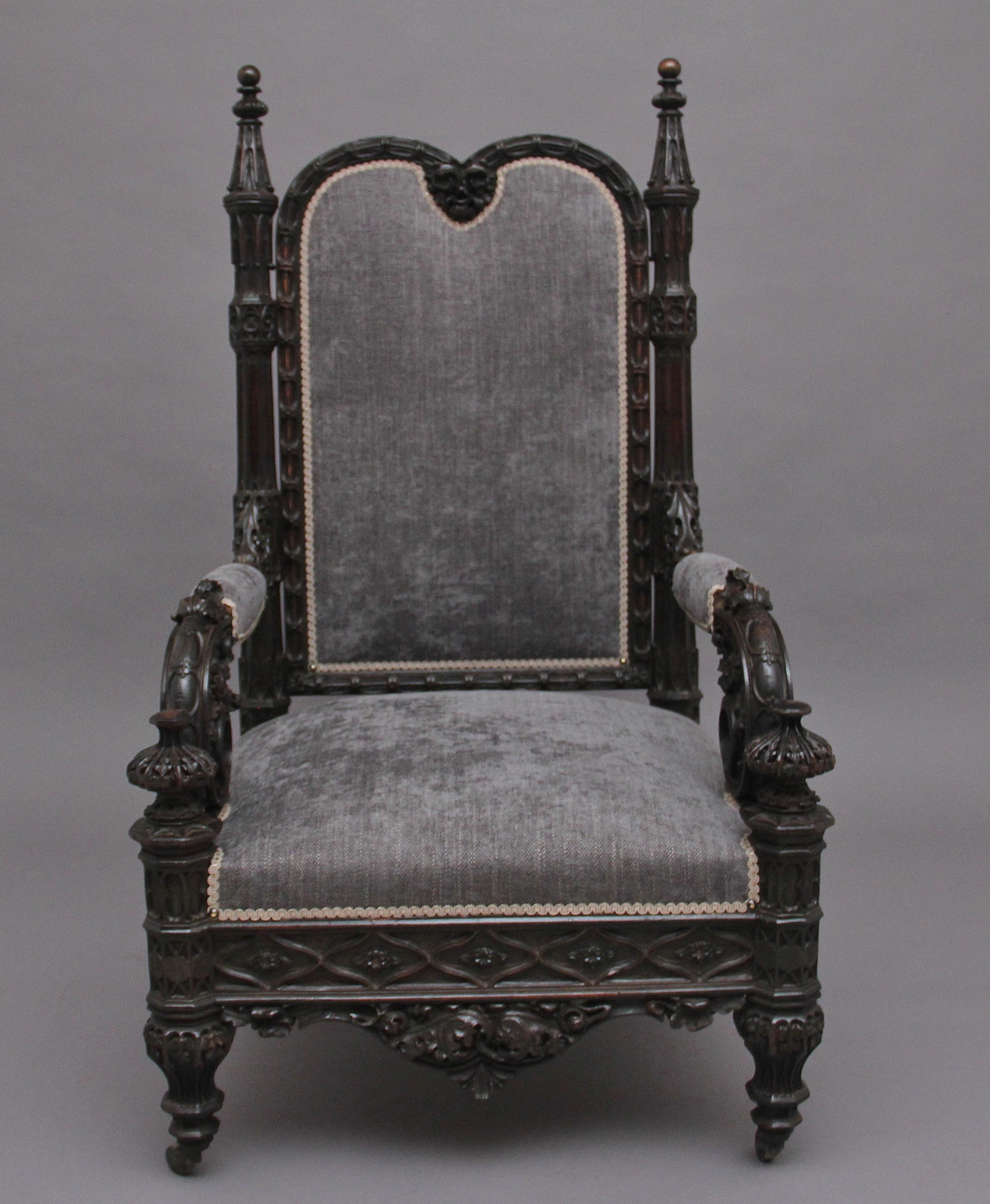 A superb quality 19th century carved Gothic style armchair, recently upholstered in a grey fabric, the arched padded back with decorative carved frame with a figure head at the top, with typical carved Gothic columns either side, padded arms and