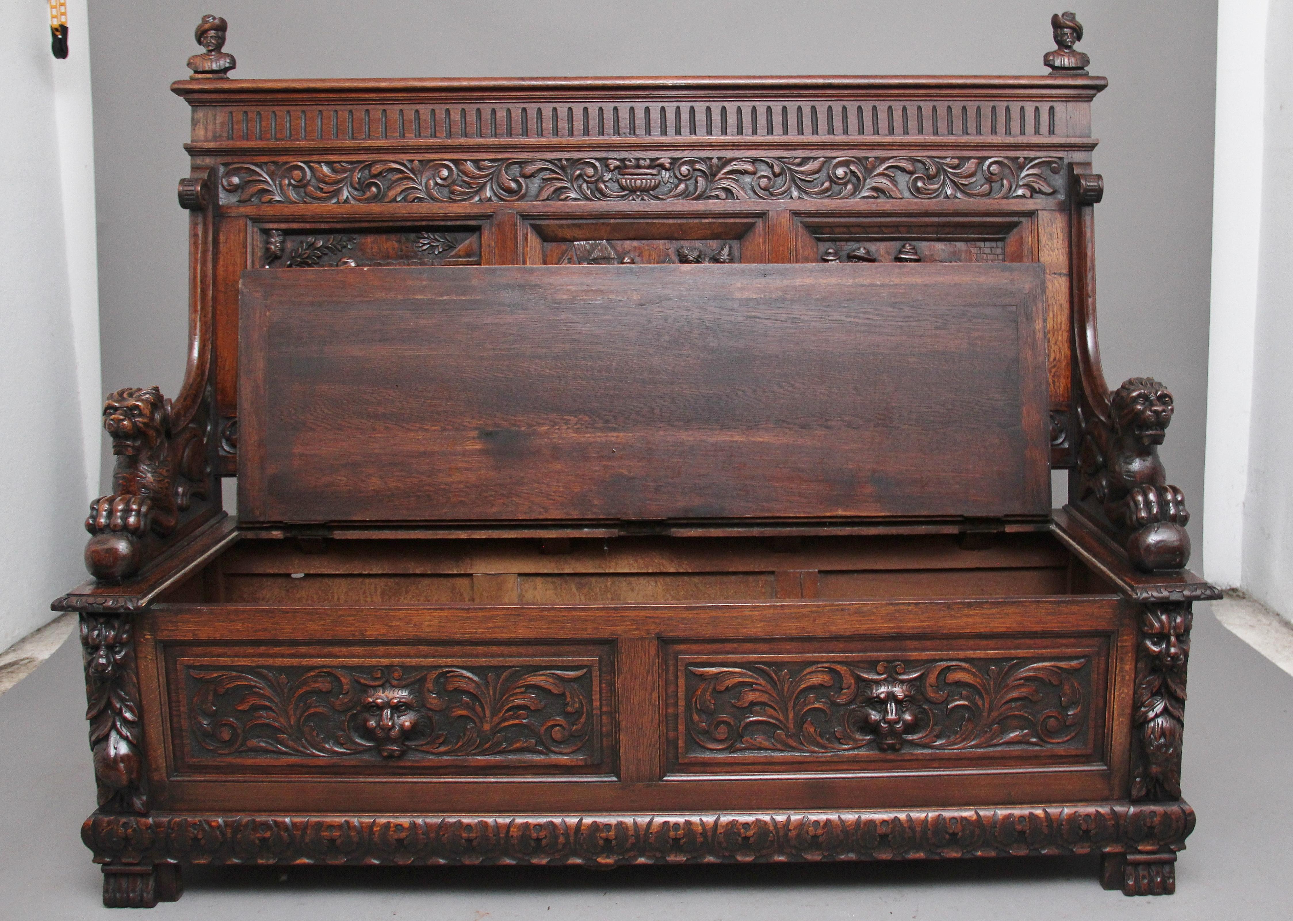 A superb quality 19th century flemish oak box settle that is very well carved, the back having three carved panels depicting tavern scenes, the top of the back having two carved figure heads above a carved frieze, the arms carved with lions with