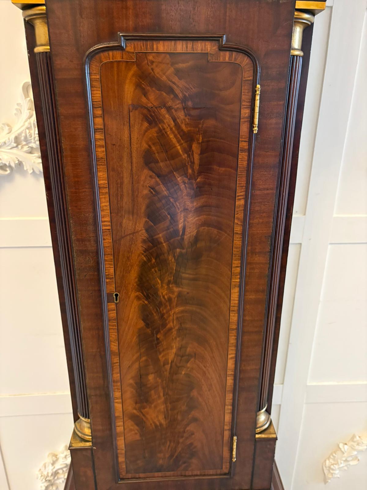 Superb quality antique George III inlaid mahogany brass face long case clock having a superb quality mahogany arch top hood with original brass galleries and finale, figured mahogany door flanked by mahogany reeded columns with gilded brass mounts,