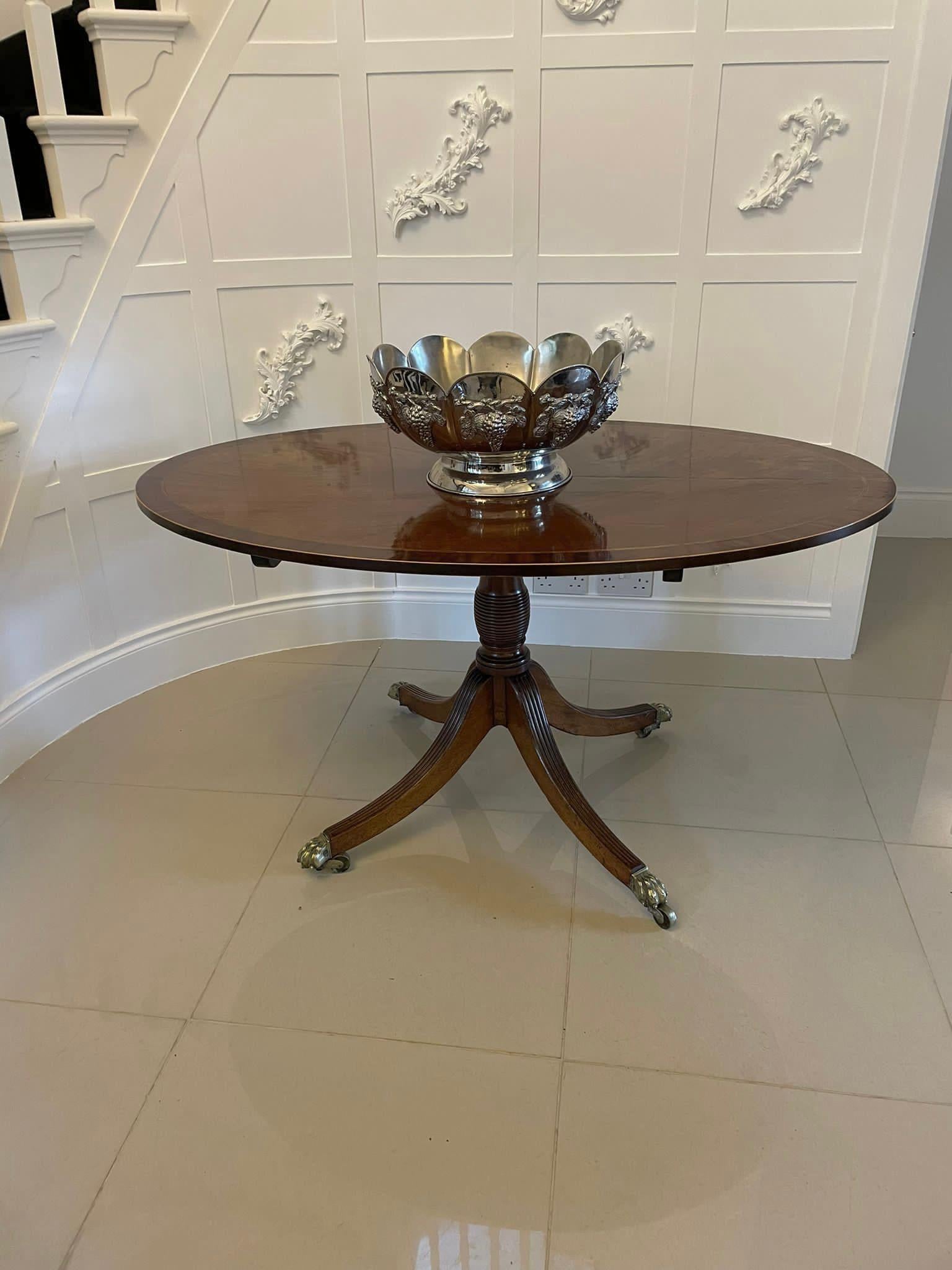 Superb quality antique George III mahogany oval centre table having a superb quality oval mahogany crossbanded tilt top with satinwood stringing supported on a turned column and raised on four shaped reeded sabre legs with original brass paw feet
