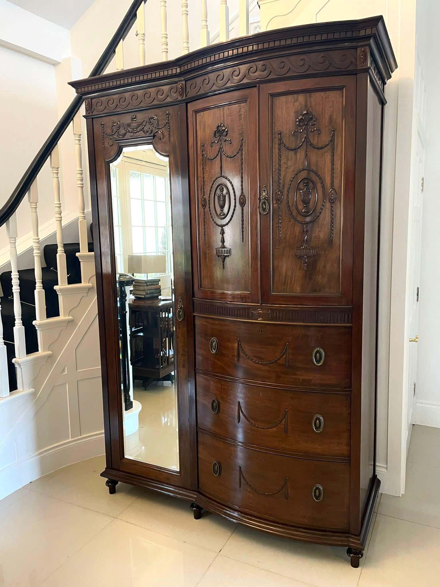 Superb quality antique Victorian carved mahogany wardrobe having a moulded cornice, carved frieze with scroll decoration above a single bevelled edge mirror door opening to reveal a hanging compartment. The pair of bow fronted doors boast superb