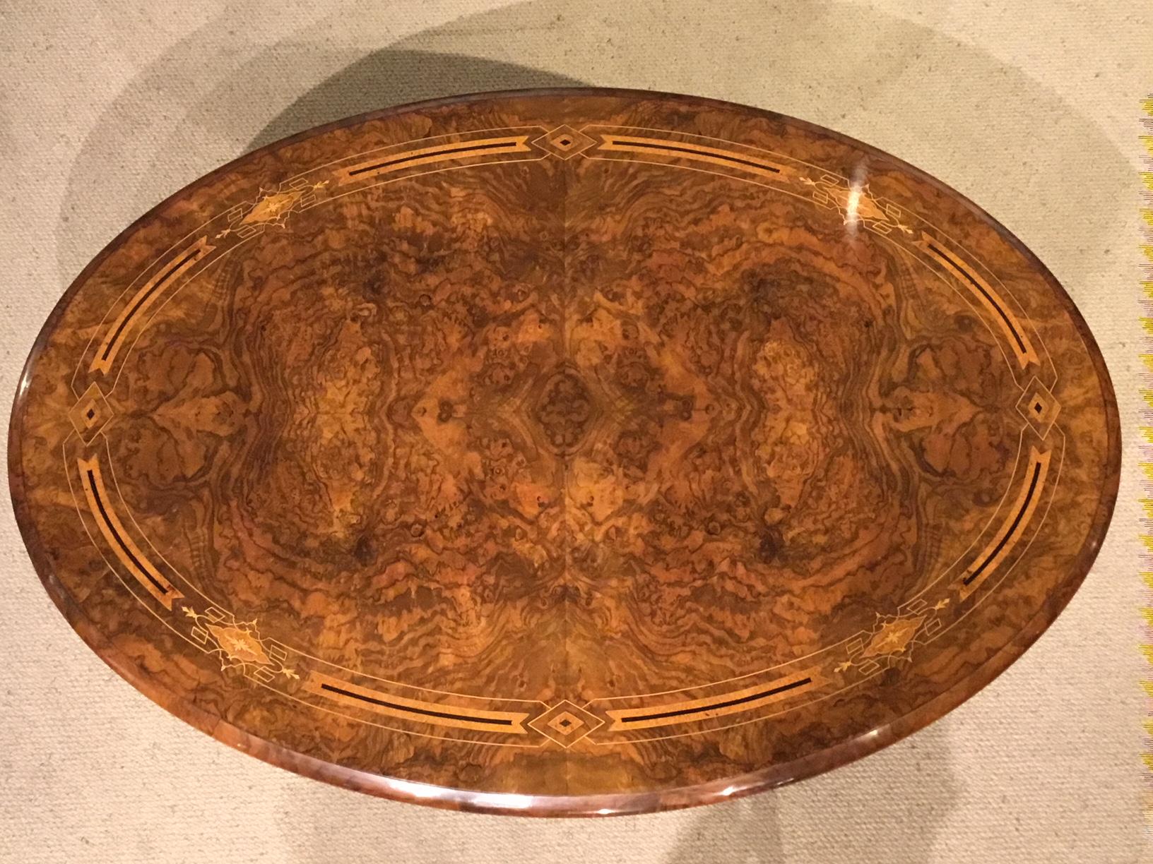 A superb quality burr walnut marquetry inlaid Victorian period antique coffee table. Having an oval top beautifully veneered in fine burr walnut with an amboyna, ebony and boxwood inlaid border. Raised on four turned column supports with a central