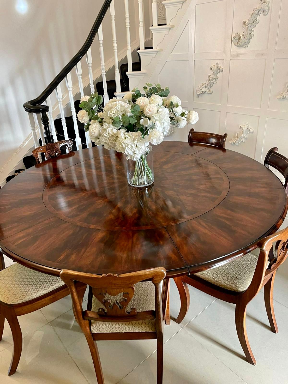 Superb quality figured mahogany circular extending dining table having a superb quality figured mahogany crossbanded circular top with a moulded edge, 6 extra leaves supported by turned mahogany columns shaped platform base standing on sabre legs