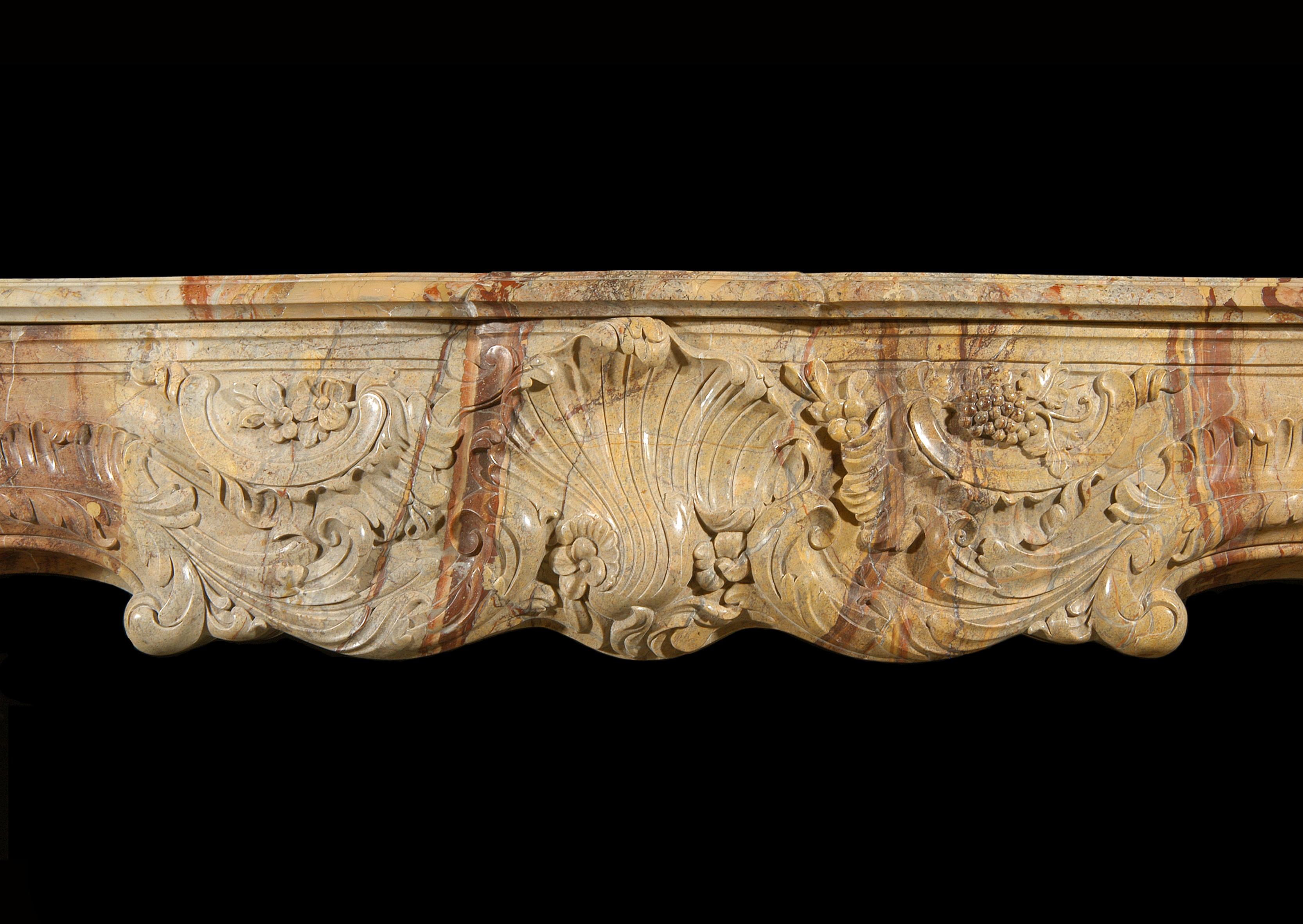 A superb quality French Louis XV style carved Sarrancolin marble fireplace, the frieze with centre shell and scrolls, foliage and grapes. The shaped jambs with stiff acanthus leaf carvings, surmounted by leaves and scrolls. Shaped serpentine