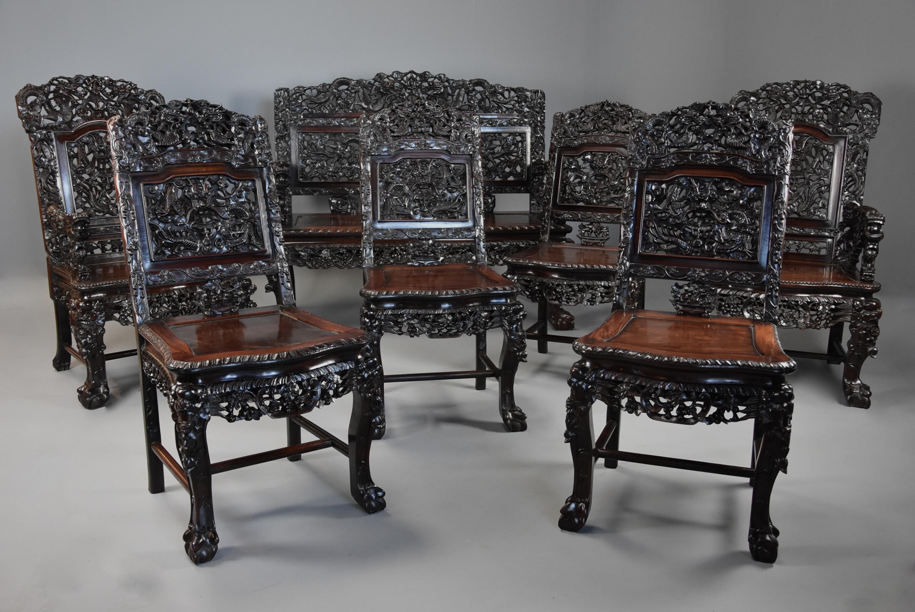 A superb quality late 19th century (circa 1880) Chinese profusely carved padouk seven piece suite.

This suite consists of a two/three-seat bench, a pair of open armchairs and four single chairs, all of exceptional quality. 

Each of the pieces