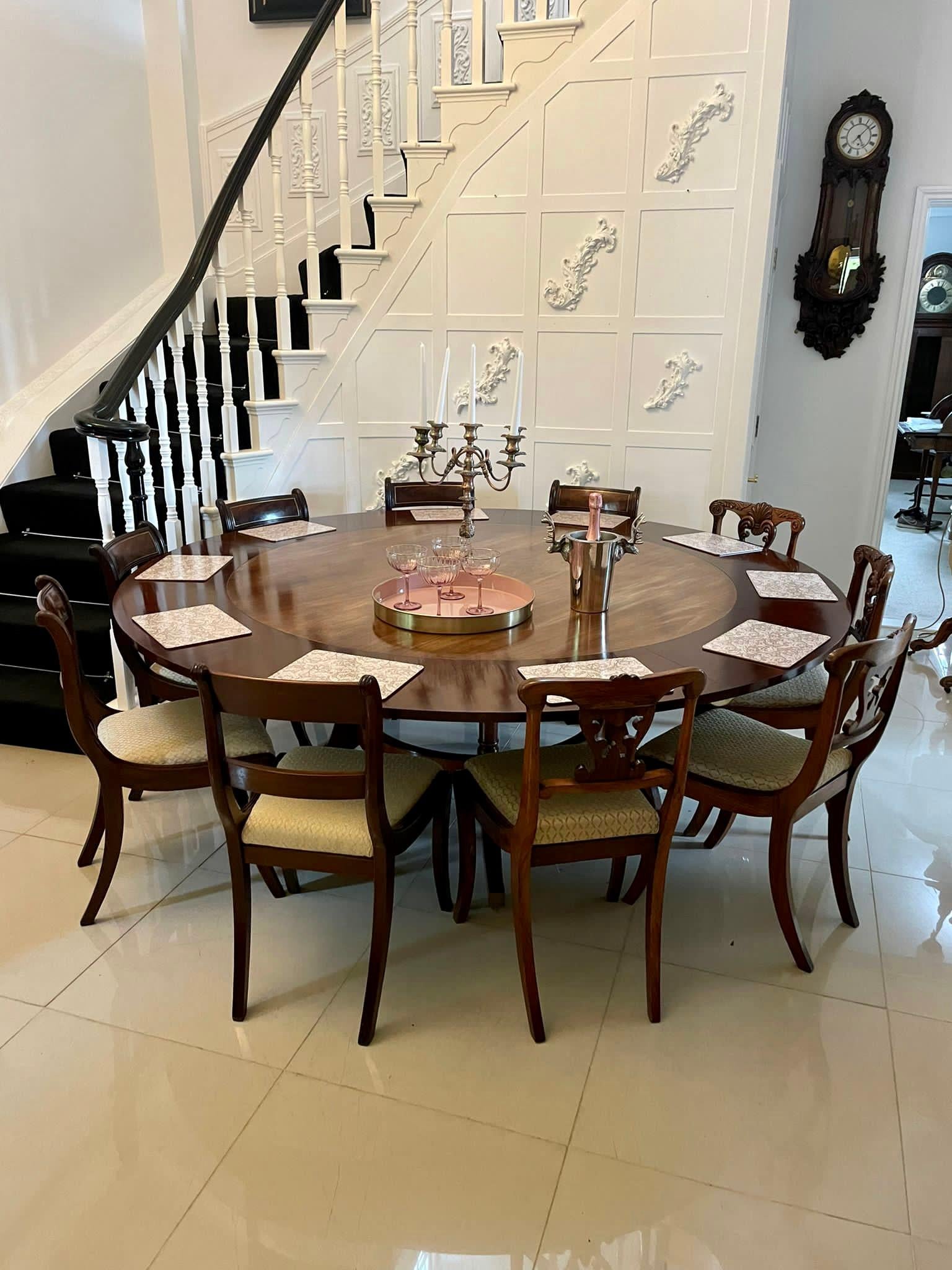 Superb quality figured mahogany antique circular extending 10 seater dining table having a moulded edge with 5 extra leaves supported by turned mahogany columns standing on shaped sabre legs with original brass feet united by a circular mahogany