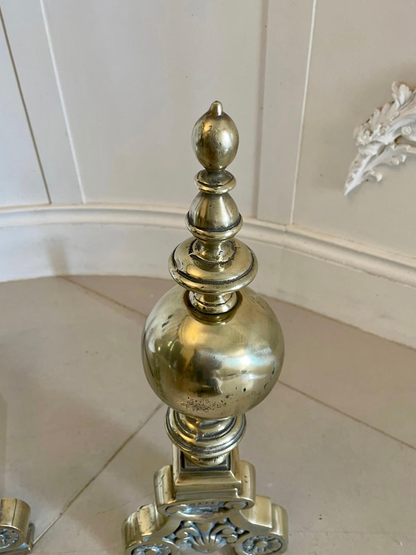 Superb quality ornate antique Victorian pair of brass fire dogs having a round ball to the top above an attractive ornate column standing on scroll feet united by an iron stand. 

Measures: H 51 x W 17 x D 37cm
Date 1850.
 
