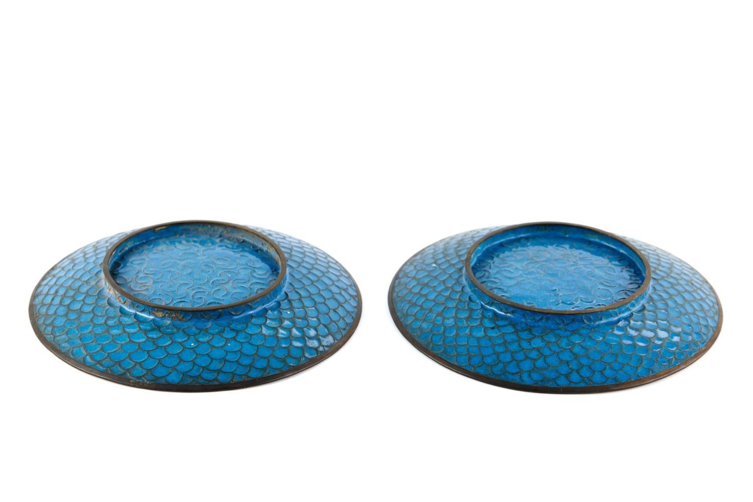 Il s'agit d'une superbe paire d'assiettes cloisonnées japonaises anciennes du début du 20e siècle. Elles présentent un magnifique fond bleu clair avec des fleurs et des feuilles roses, vertes, rouges et grises.