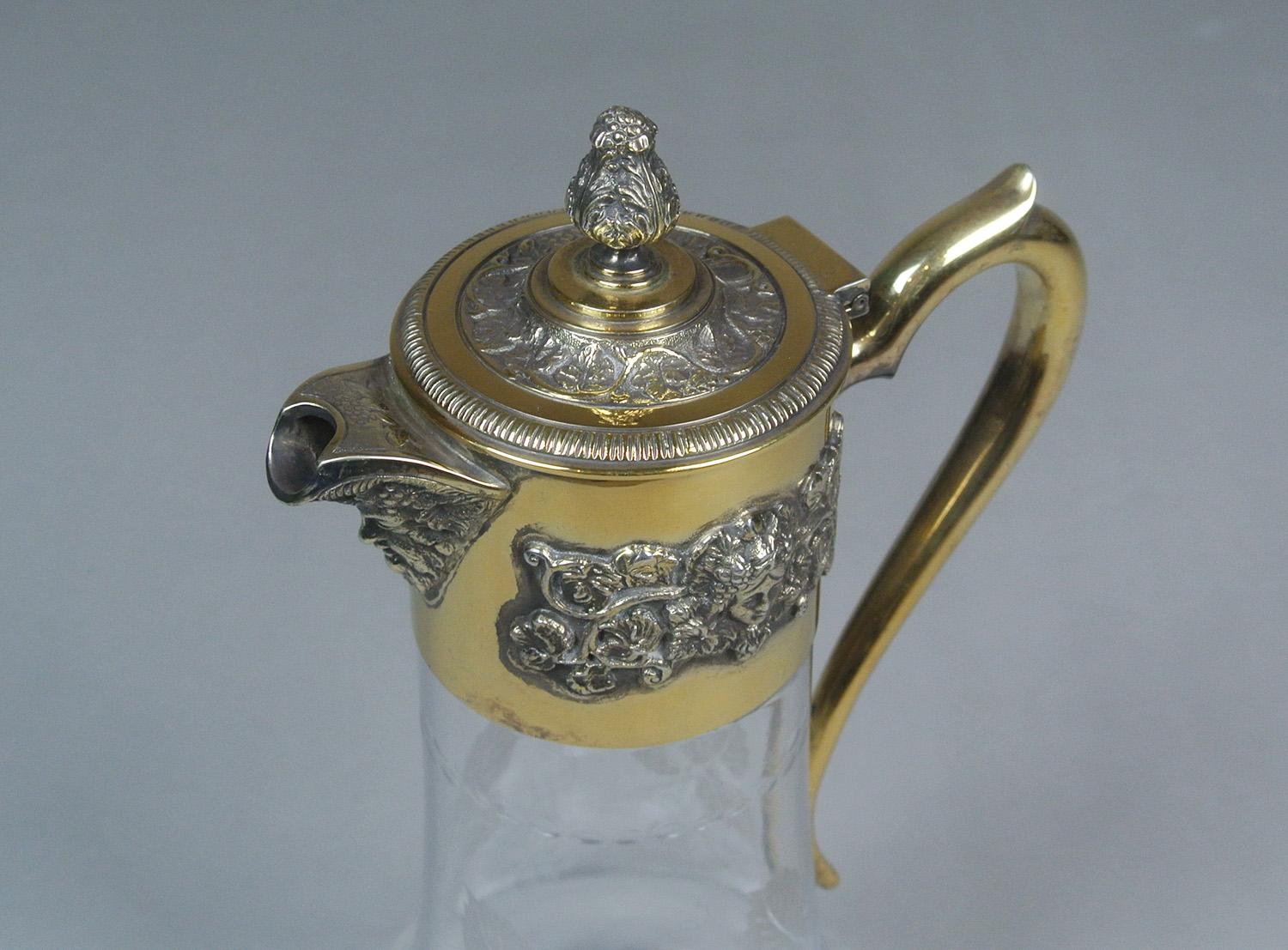 A beautiful crystal claret jug made by Asprey & Co with solid silver and gold gilded mount applied with Bacchanalian masks and vines, the spout formed as Bacchus mask, the hinged cover with acanthus bud, silver stamped and Asprey marked on mount and