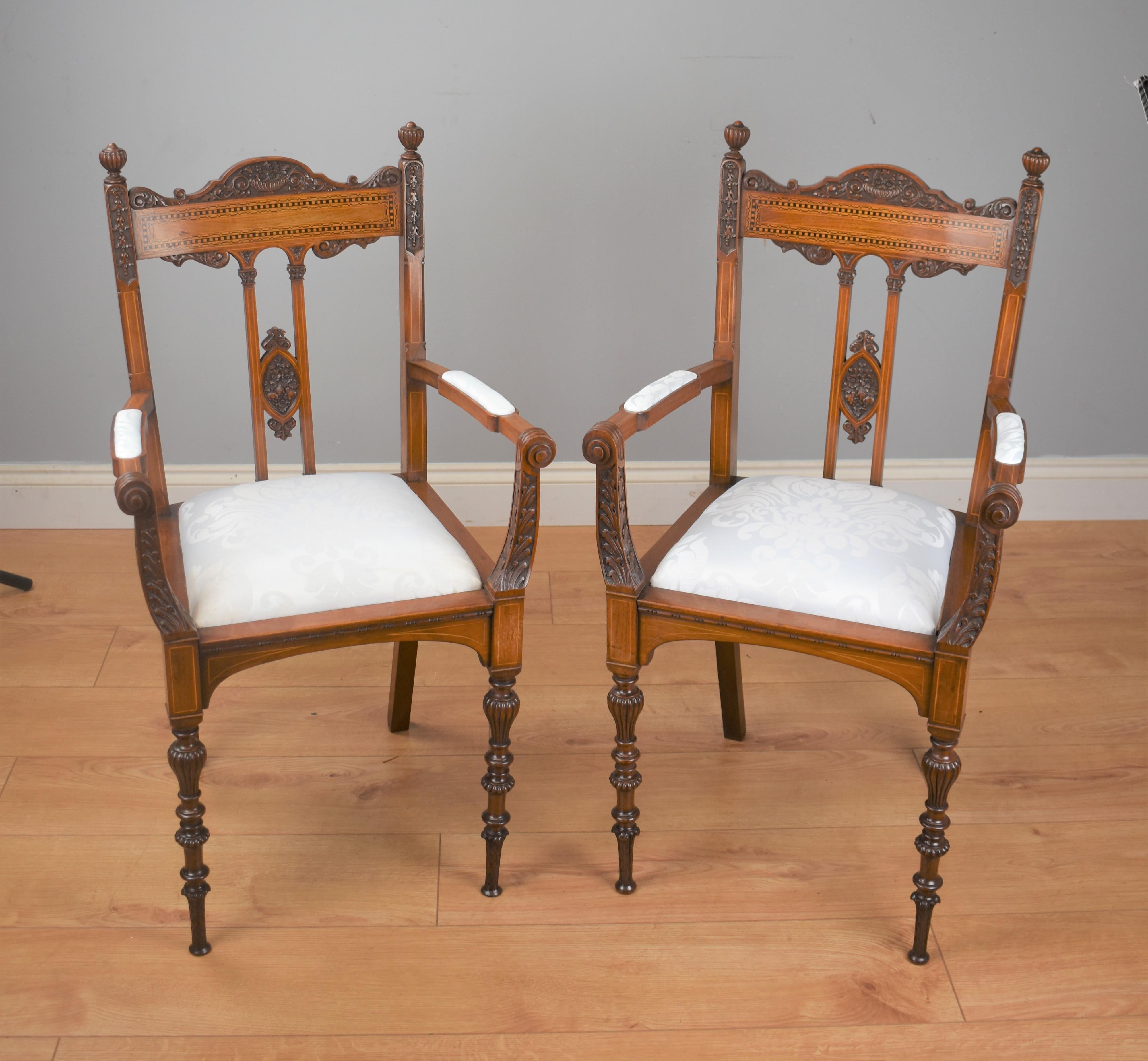 A pair of Victorian inlaid mahogany chairs of exhibition quality attributed to James Shoolbred, a good example of fine hand carving, the seats are upholstered in a white patterened material.

Dimensions:
 Width 20