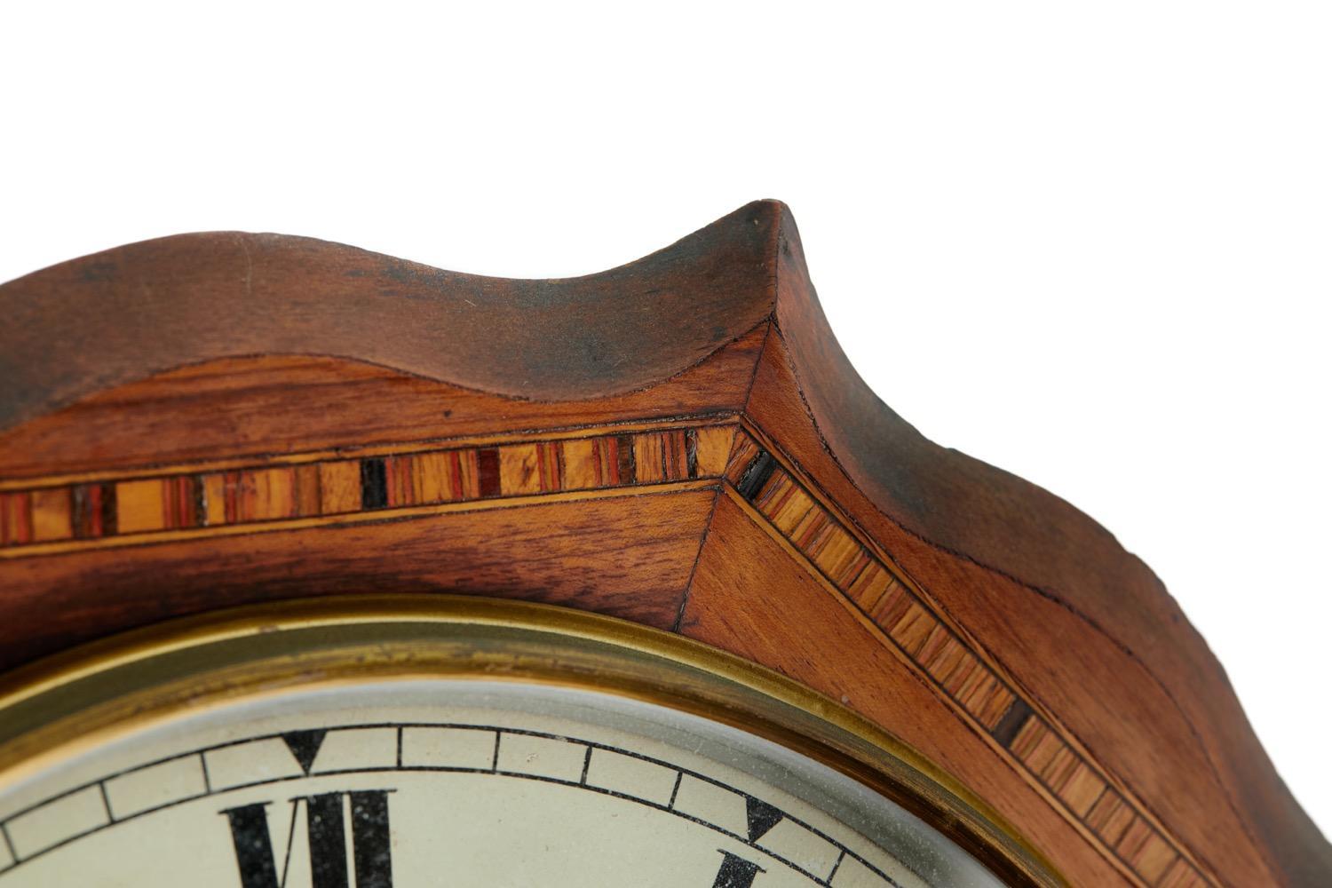 This is a superb quality mid 19th Century Victorian antique walnut inlaid drop dial wall clock having a quality inlaid shaped case, brass bezel holding a glass door covering the circular dial with original hands. The pendulum encased by an inlaid