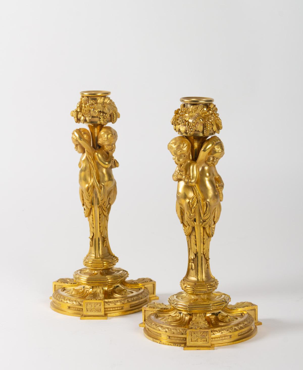 Superb, rare pair of chiselled gilt bronze candlesticks, Louis XVI style, by Henry Dasson, France, 1882, 
Signed and dated 
representing 2 cherubs holding garlands of flowers and fruits resting on richly decorated Louis XVI style